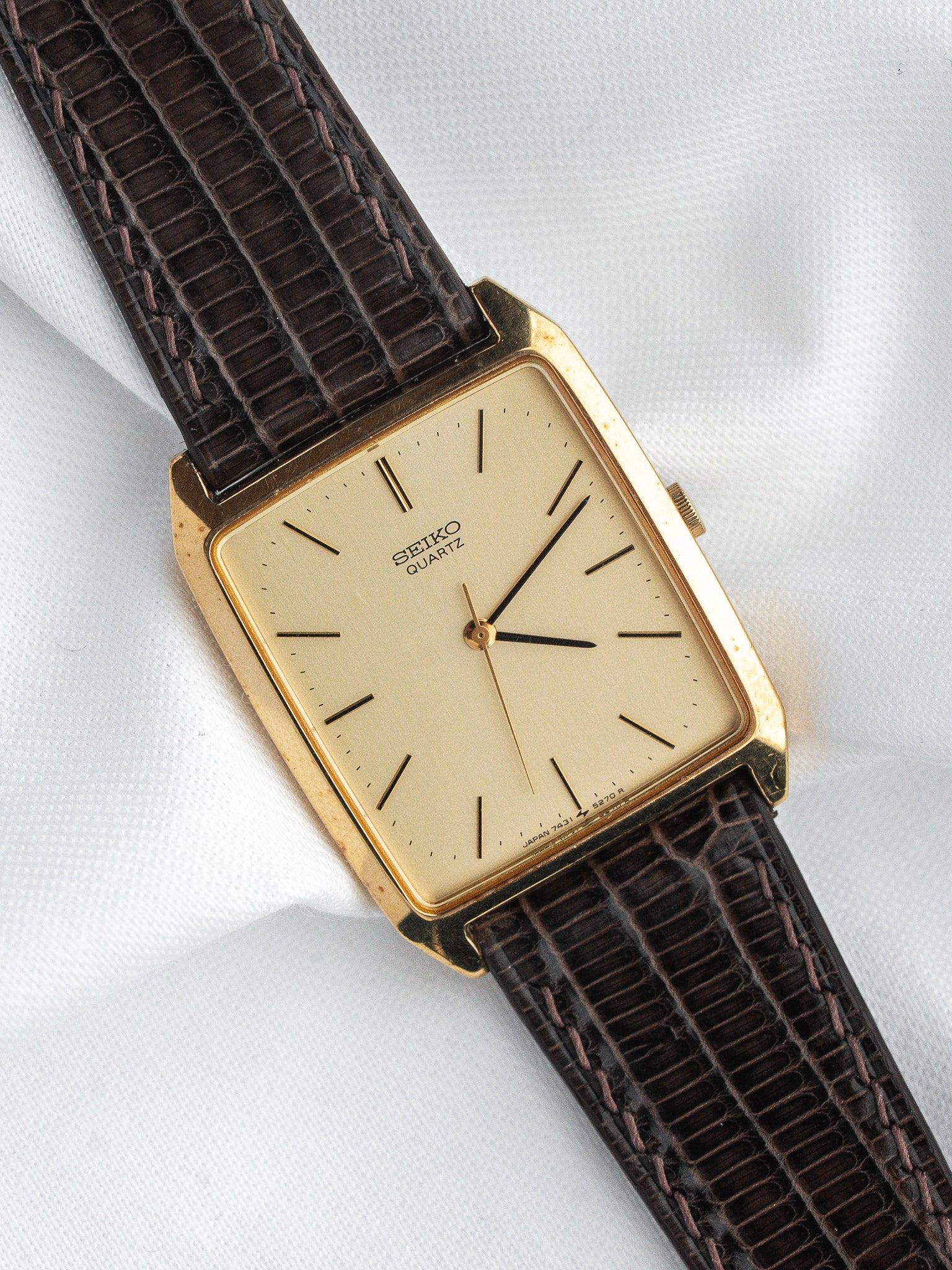 Vintage Seiko Quartz watch with gold case, cream dial, and brown lizard strap on white background
