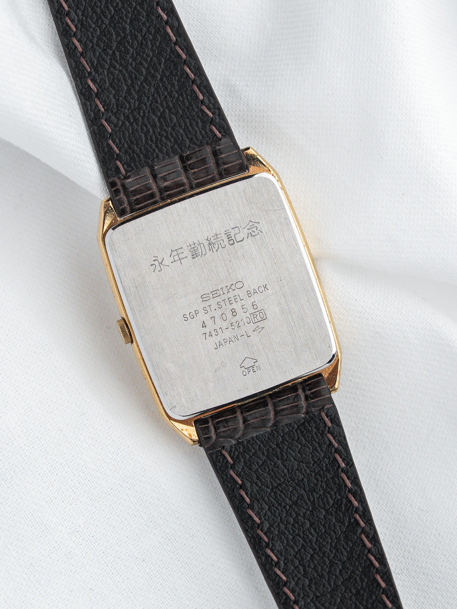 Seiko vintage watch with gold case, black leather strap, and engraved steel back