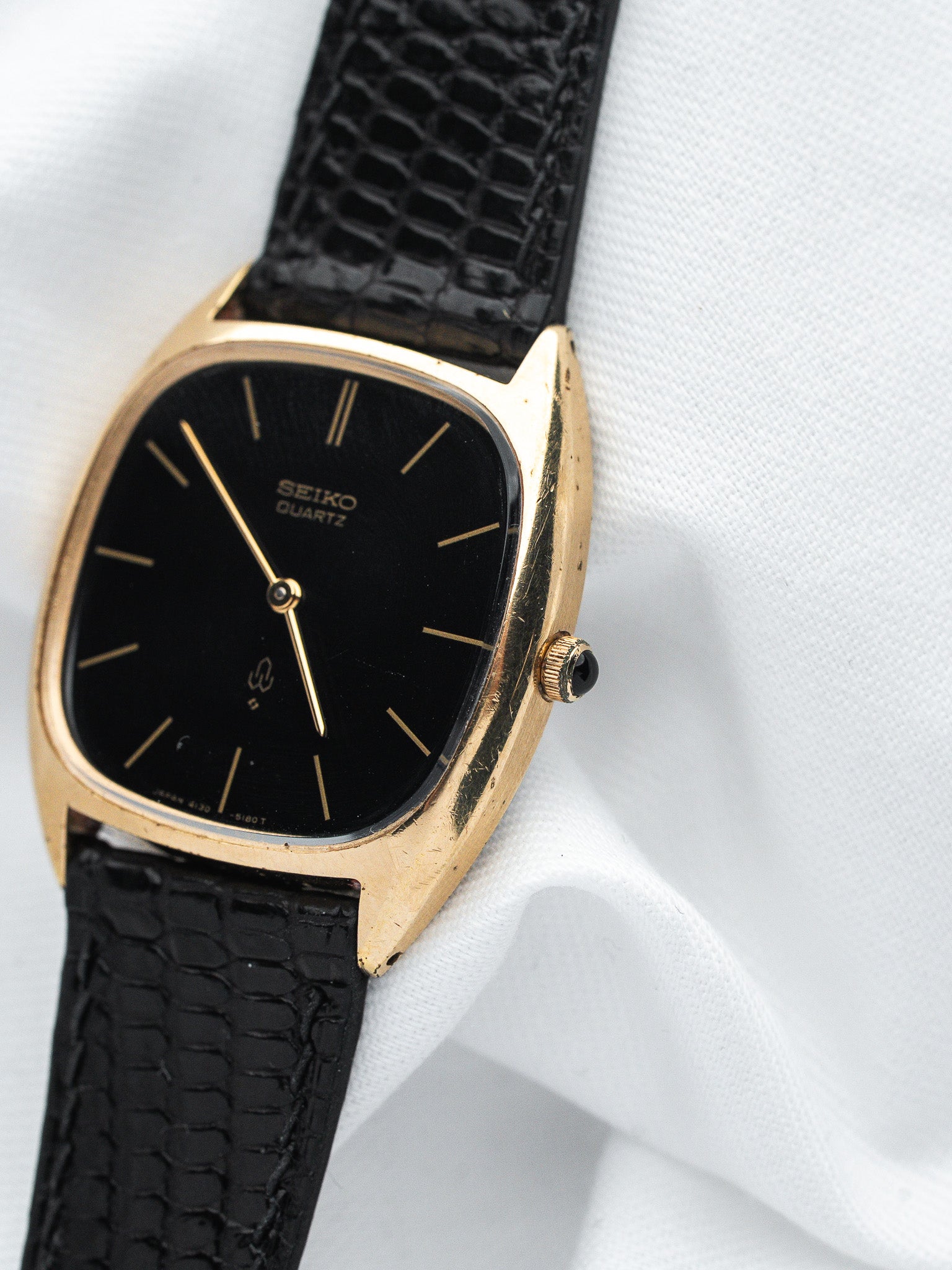 Seiko Quartz vintage watch with gold case, black dial, and textured strap