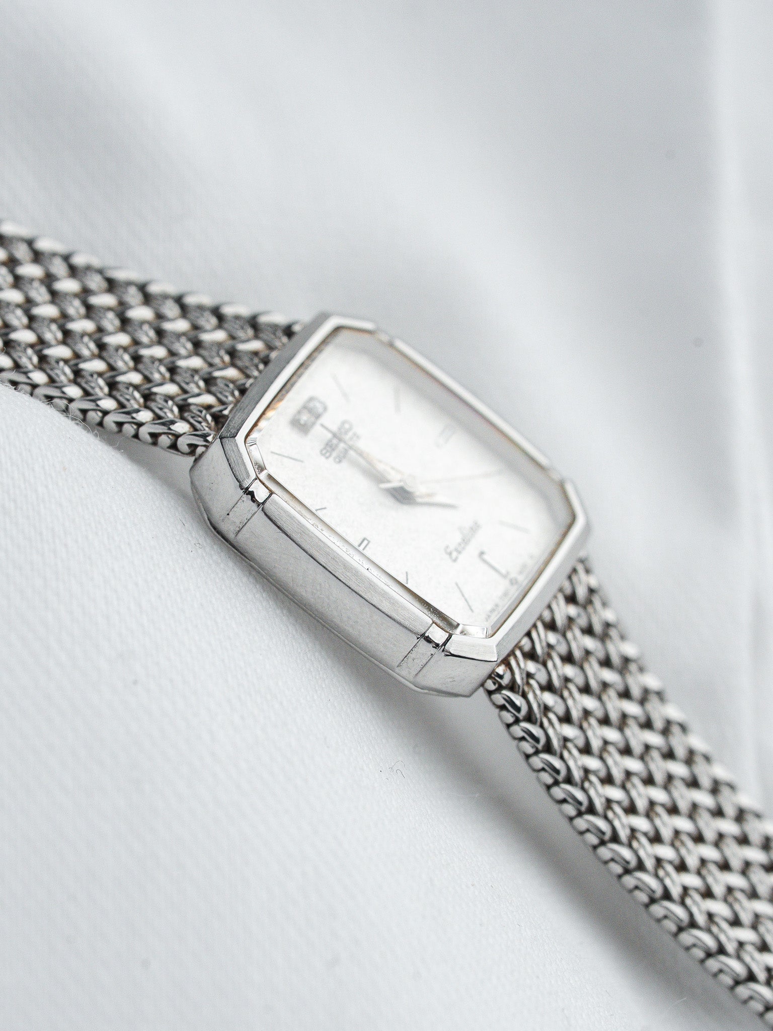 Ebel vintage watch with white dial, silver case, and mesh bracelet on fabric
