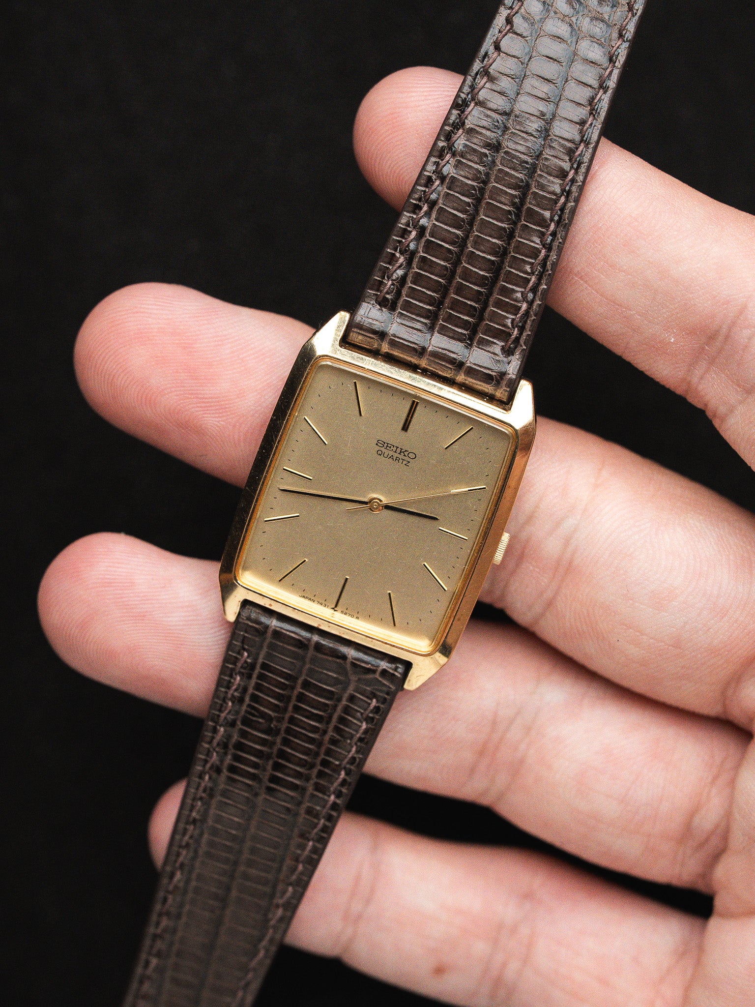 Seiko Quartz vintage watch with gold case, brown lizard strap, held in hand