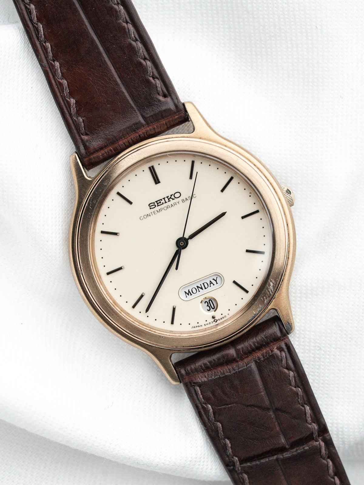 Montre Seiko vintage avec cadran crème et bracelet en cuir marron foncé.
