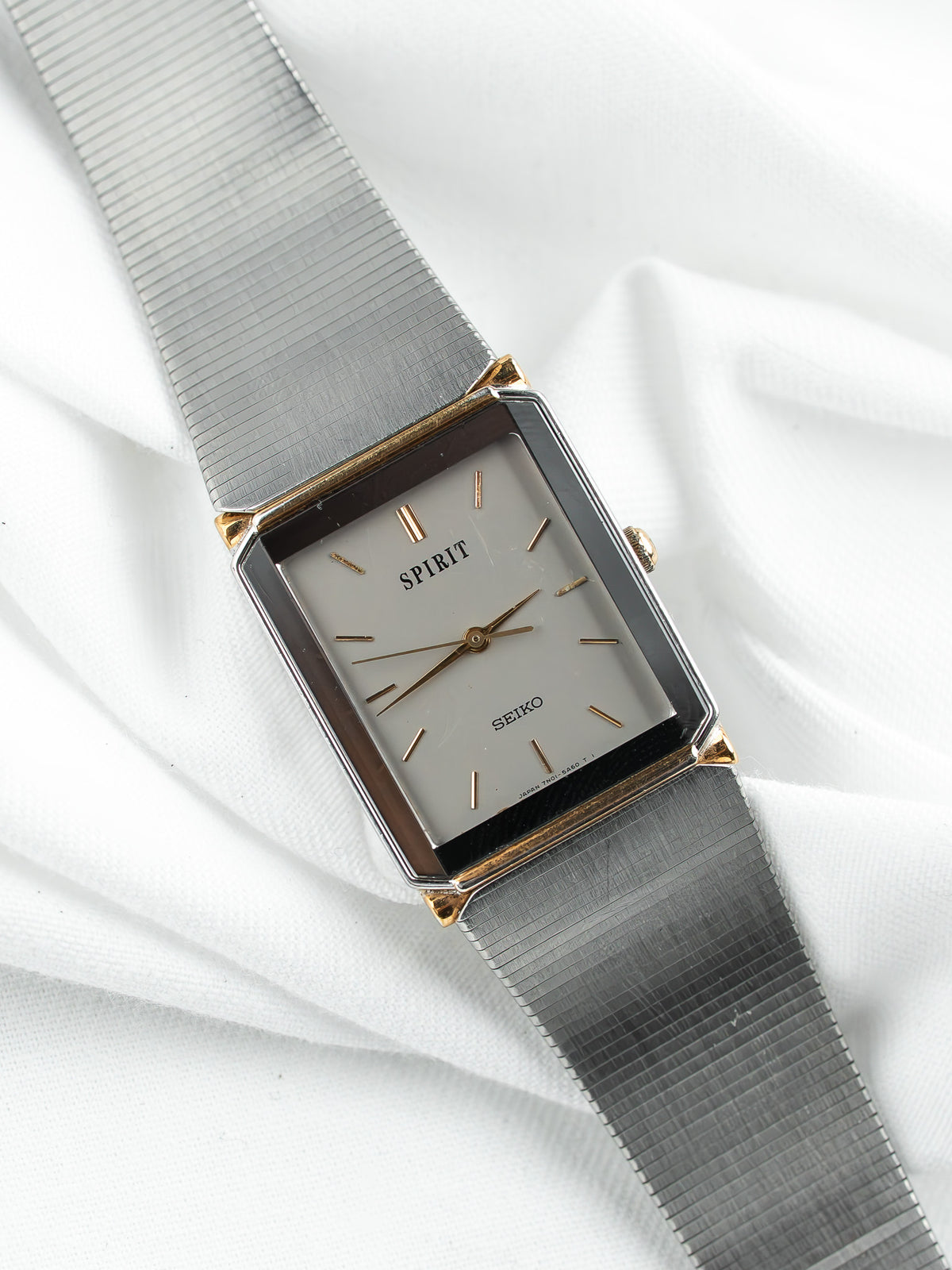 Montre Seiko Spirit vintage au cadran rectangulaire argenté et bracelet en maille métal.
