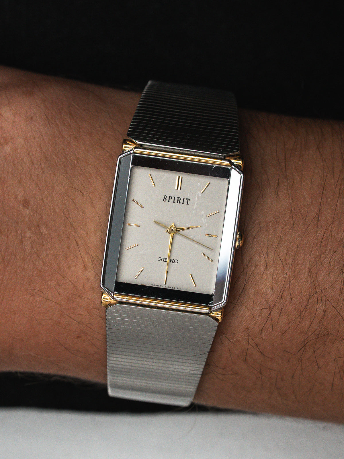 Montre Seiko Spirit vintage à boîtier rectangulaire doré et bracelet extensible en acier.