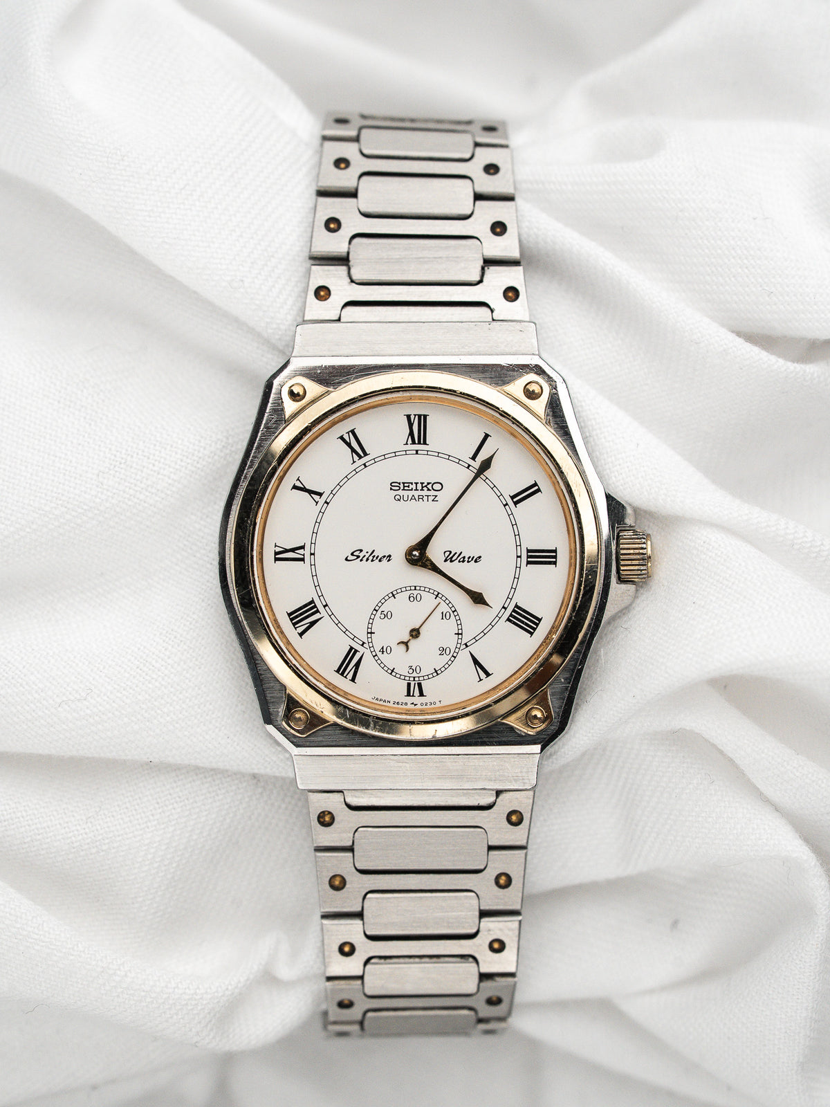 Vintage Seiko Silver Wave Watch in steel and gold, white dial, on a white background