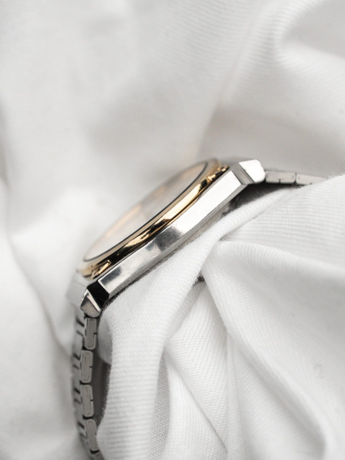 Vintage watch in steel and gold with metal bracelet on a white fabric background