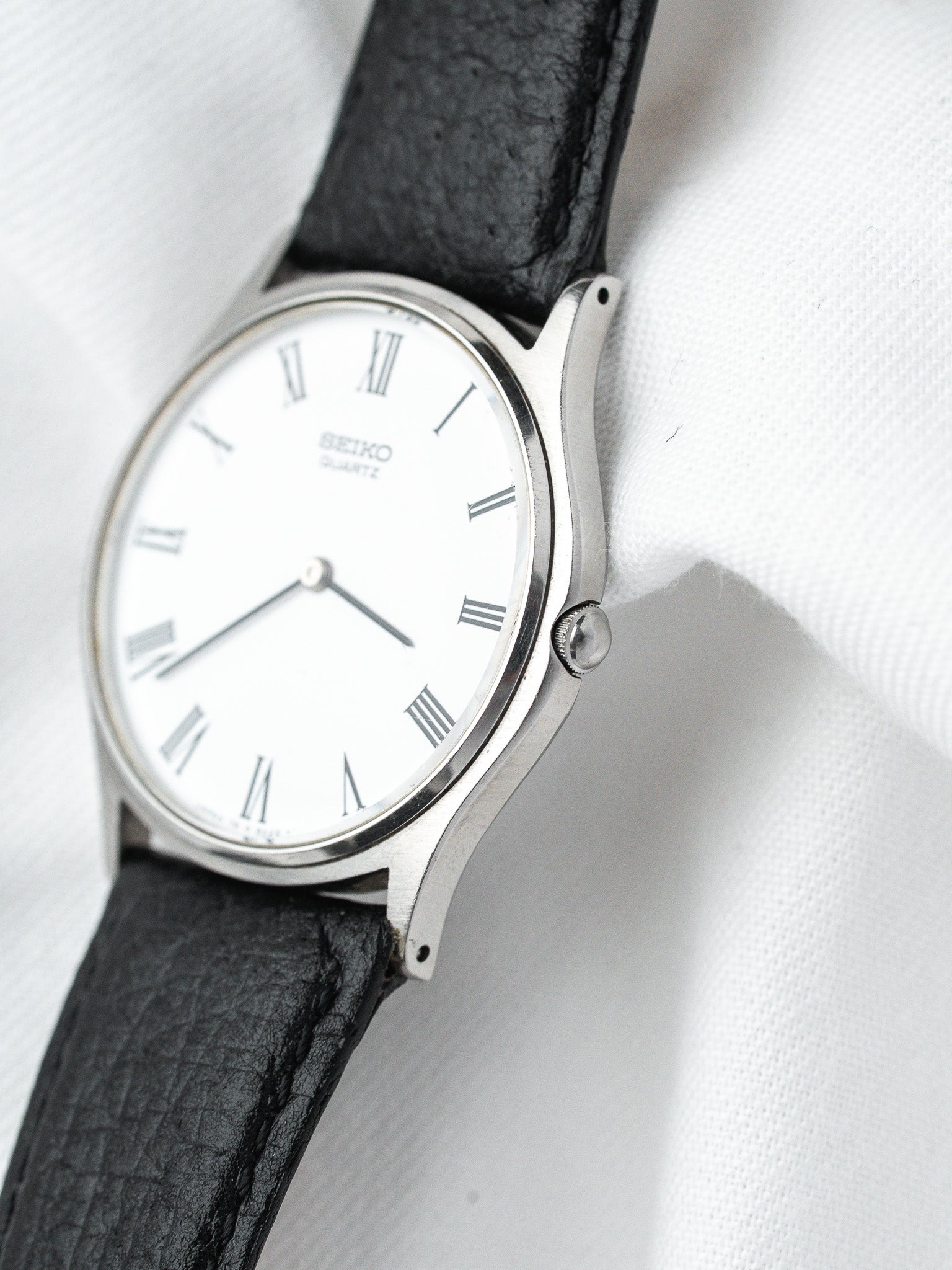 Seiko quartz vintage watch with white dial, Roman numerals, black leather strap