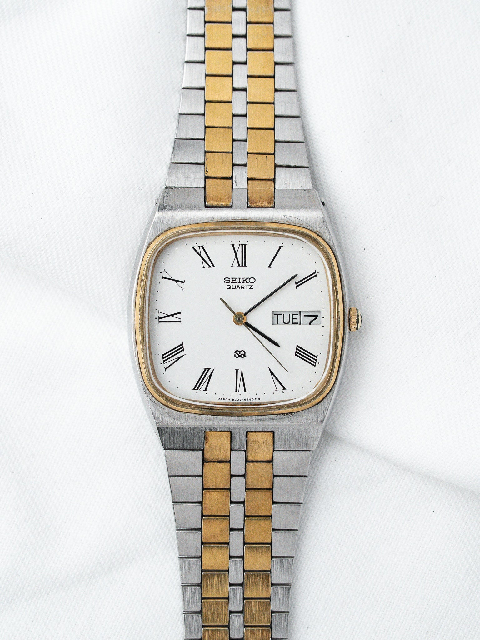 Seiko Quartz vintage watch with white dial, Roman numerals, two-tone bracelet on white background