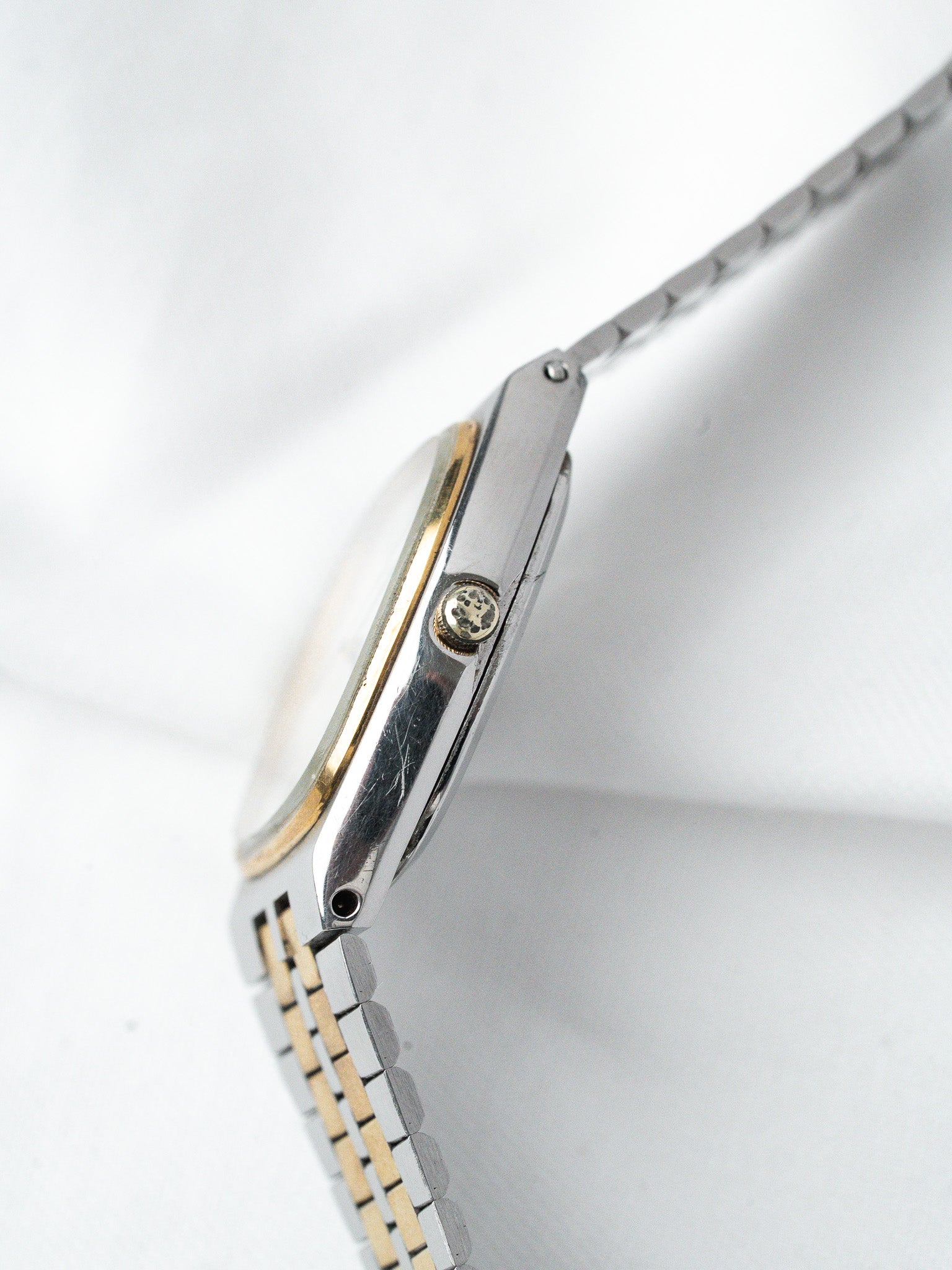 Vintage Omega watch with two-tone steel and gold bracelet, side view on white background
