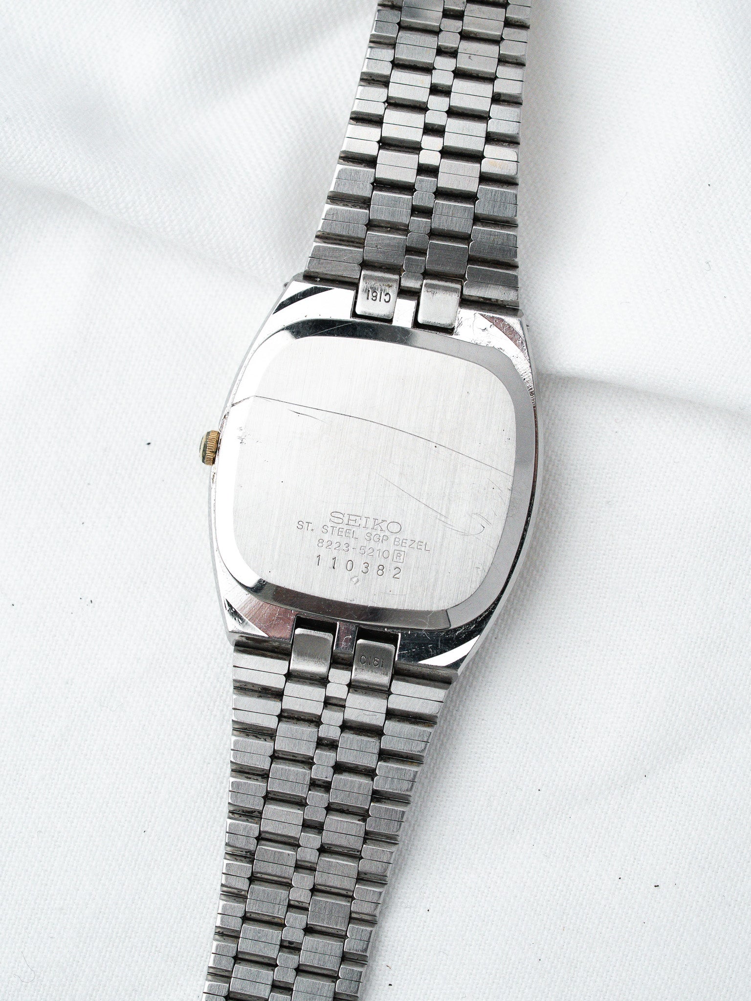 Vintage Seiko watch with stainless steel case and bracelet, back view on white fabric