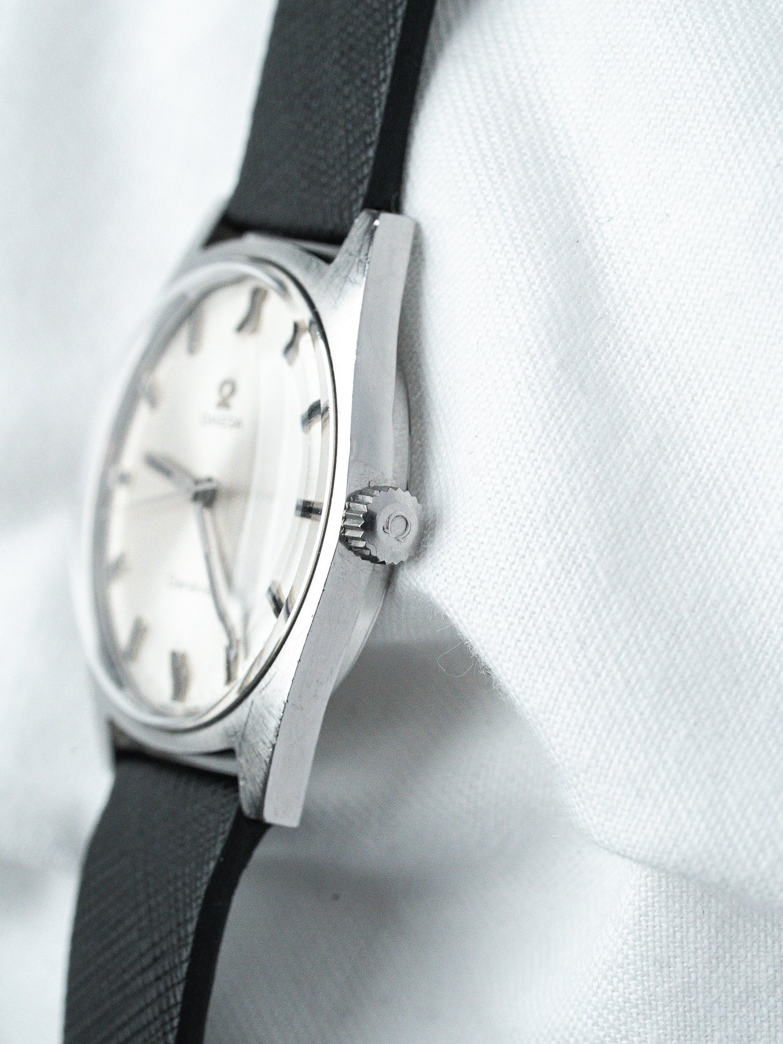 Vintage Omega watch with white dial, black strap, and stainless steel case