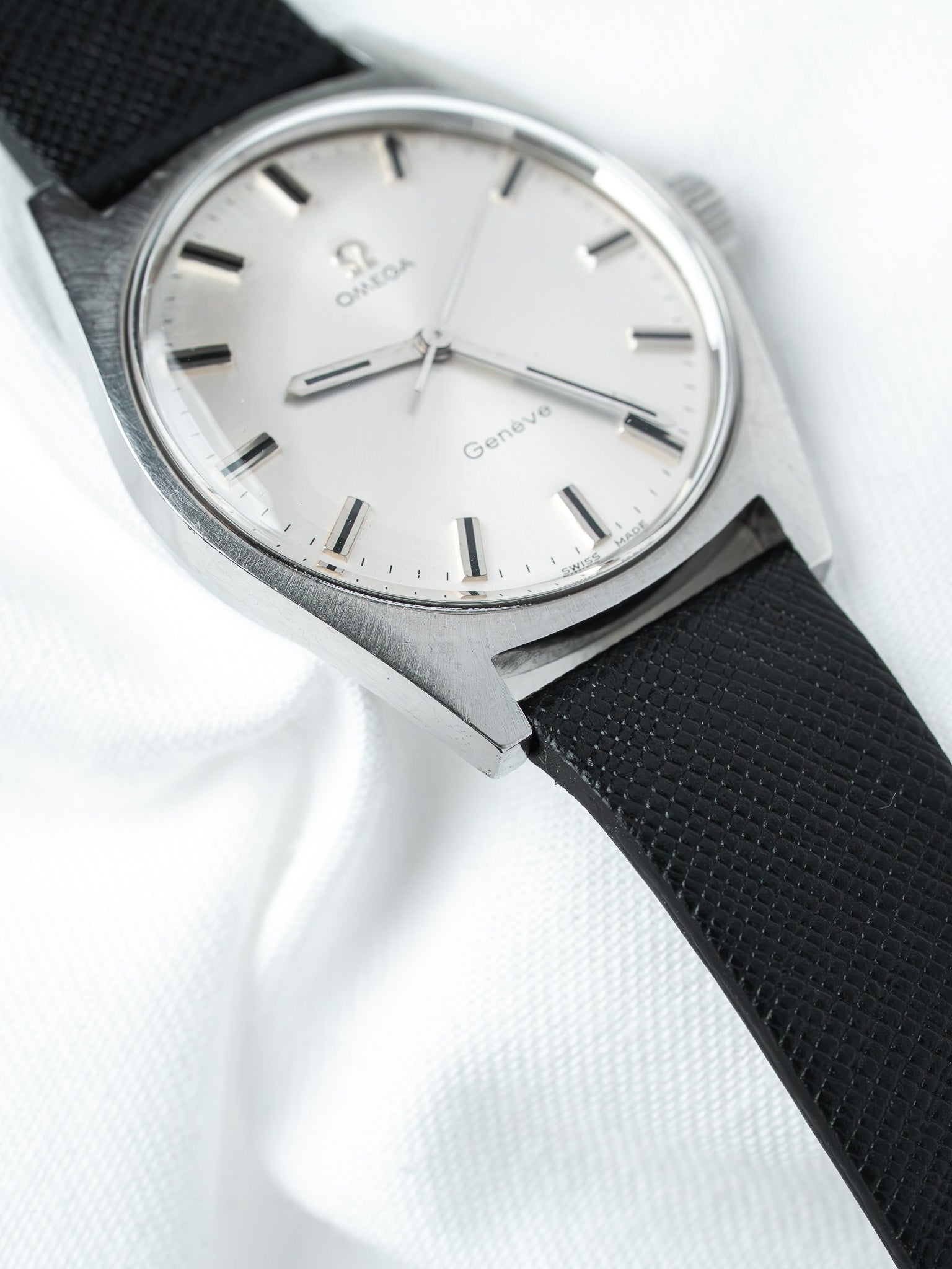 Omega Genève vintage watch with white dial, black strap, and stainless steel case