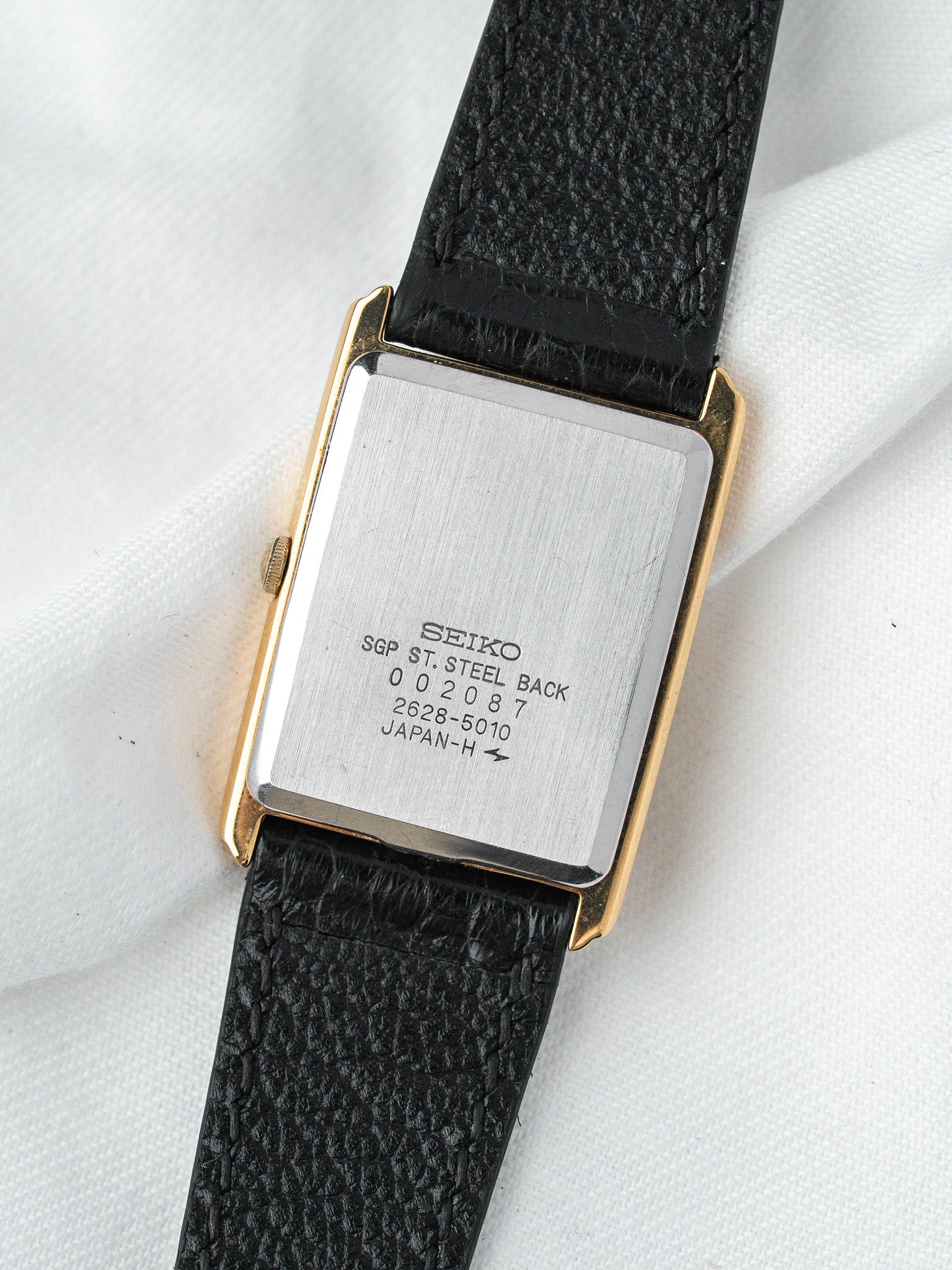 Seiko vintage watch with gold-tone case, black leather strap, stainless steel back engraved
