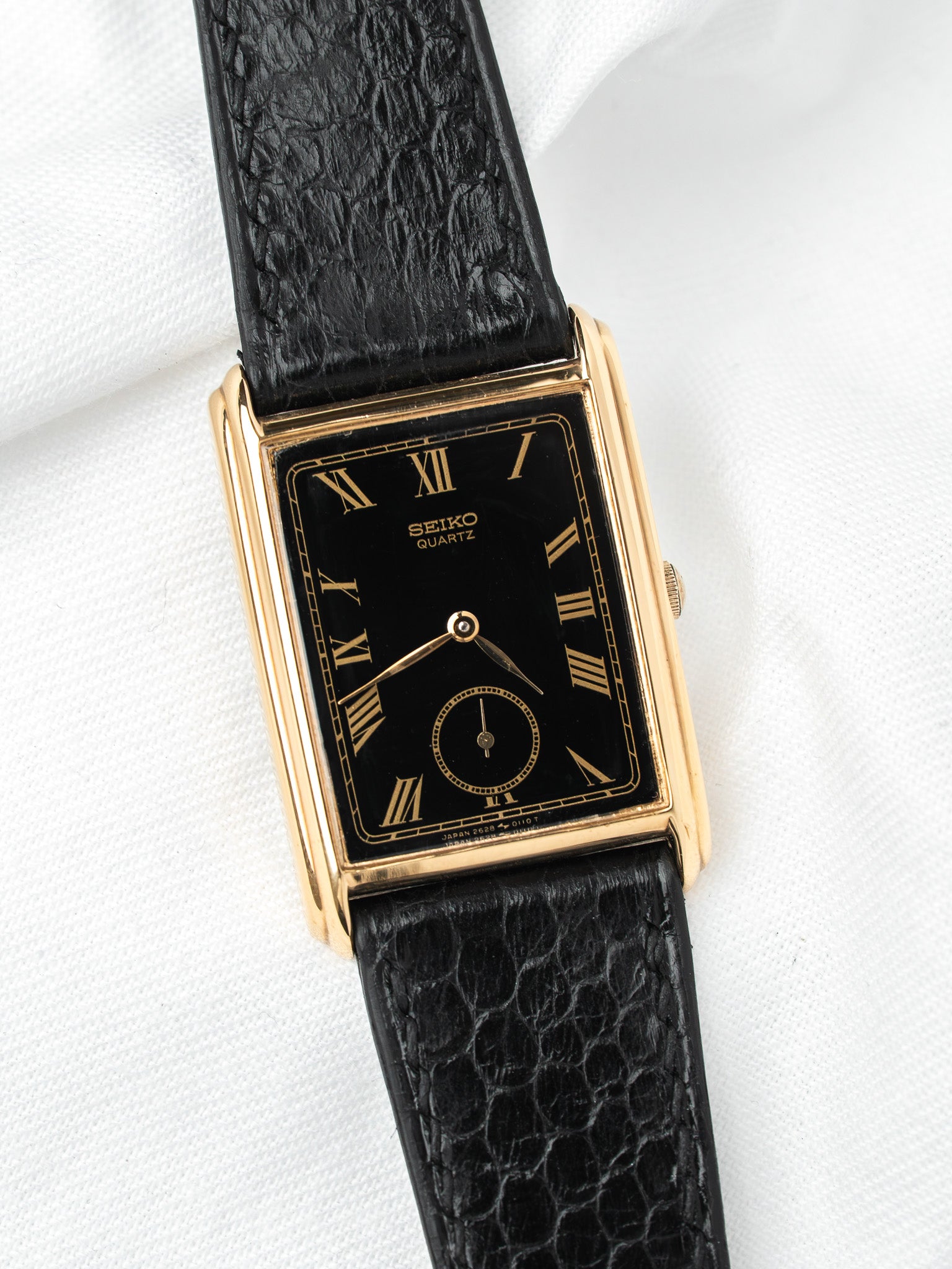 Seiko Quartz vintage watch with gold case, black dial, and textured leather strap