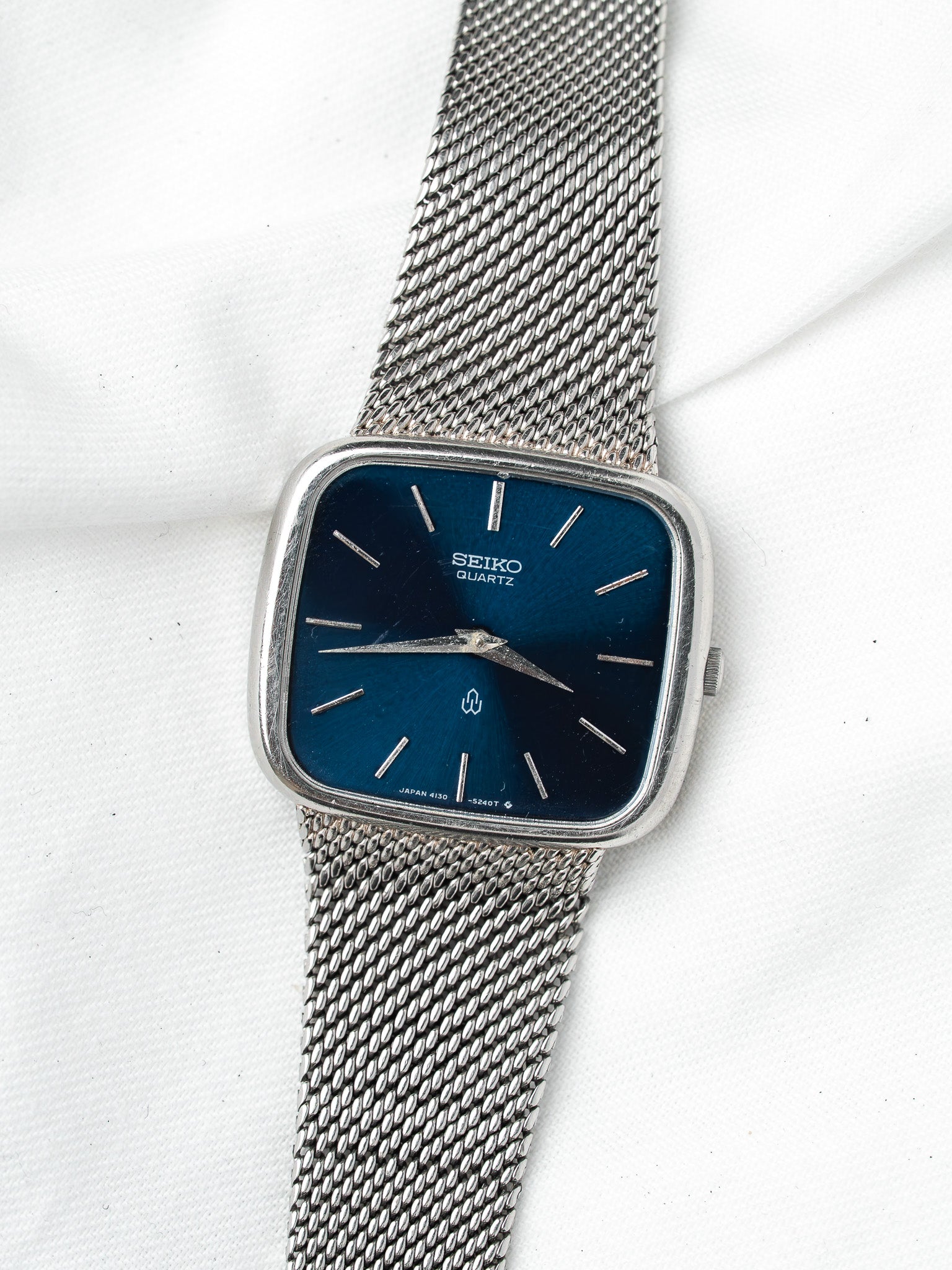 Seiko Quartz vintage watch with blue dial, silver mesh bracelet, square case on white background