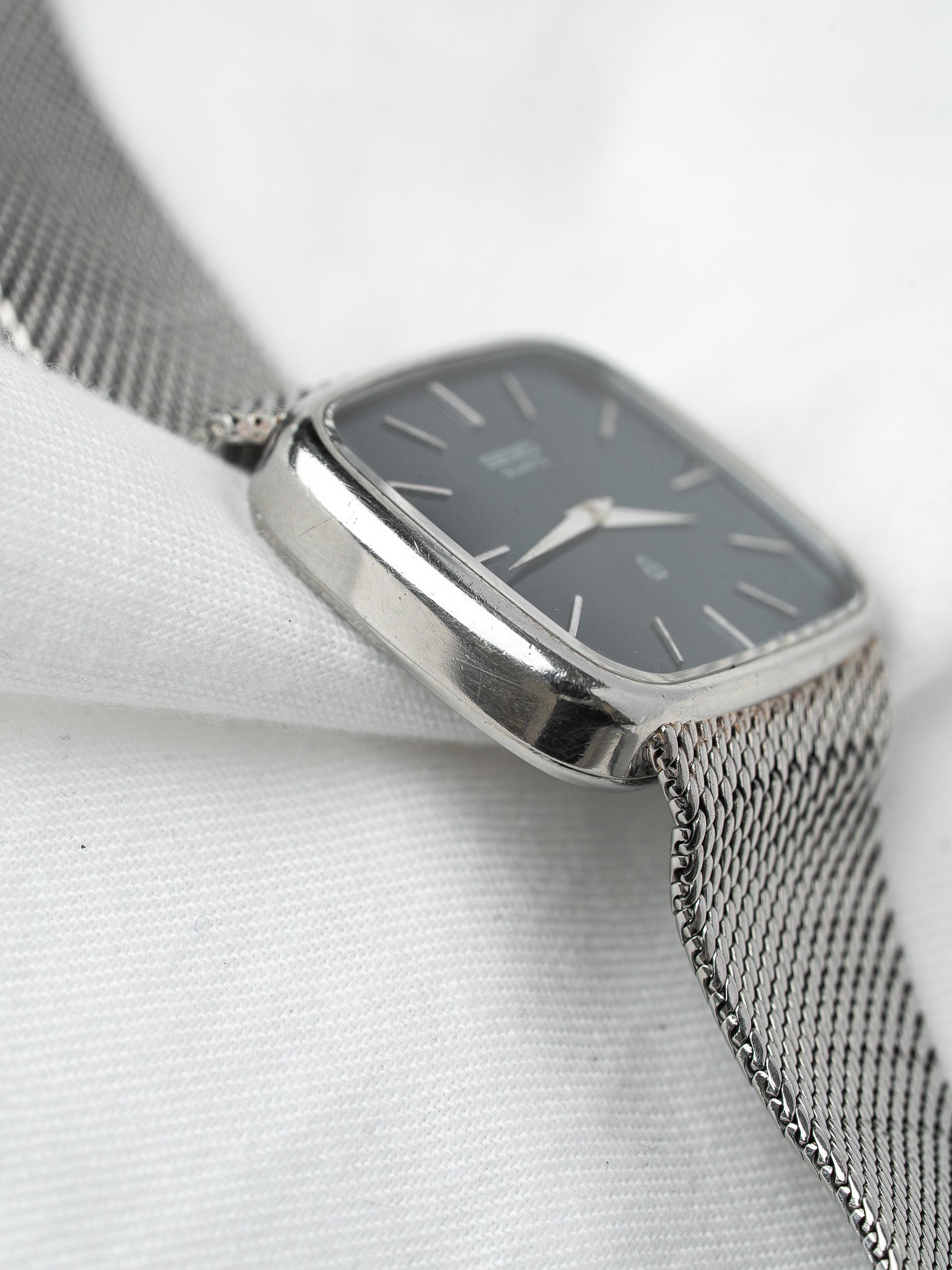 Vintage Omega watch with gray dial, silver mesh bracelet, and rectangular case