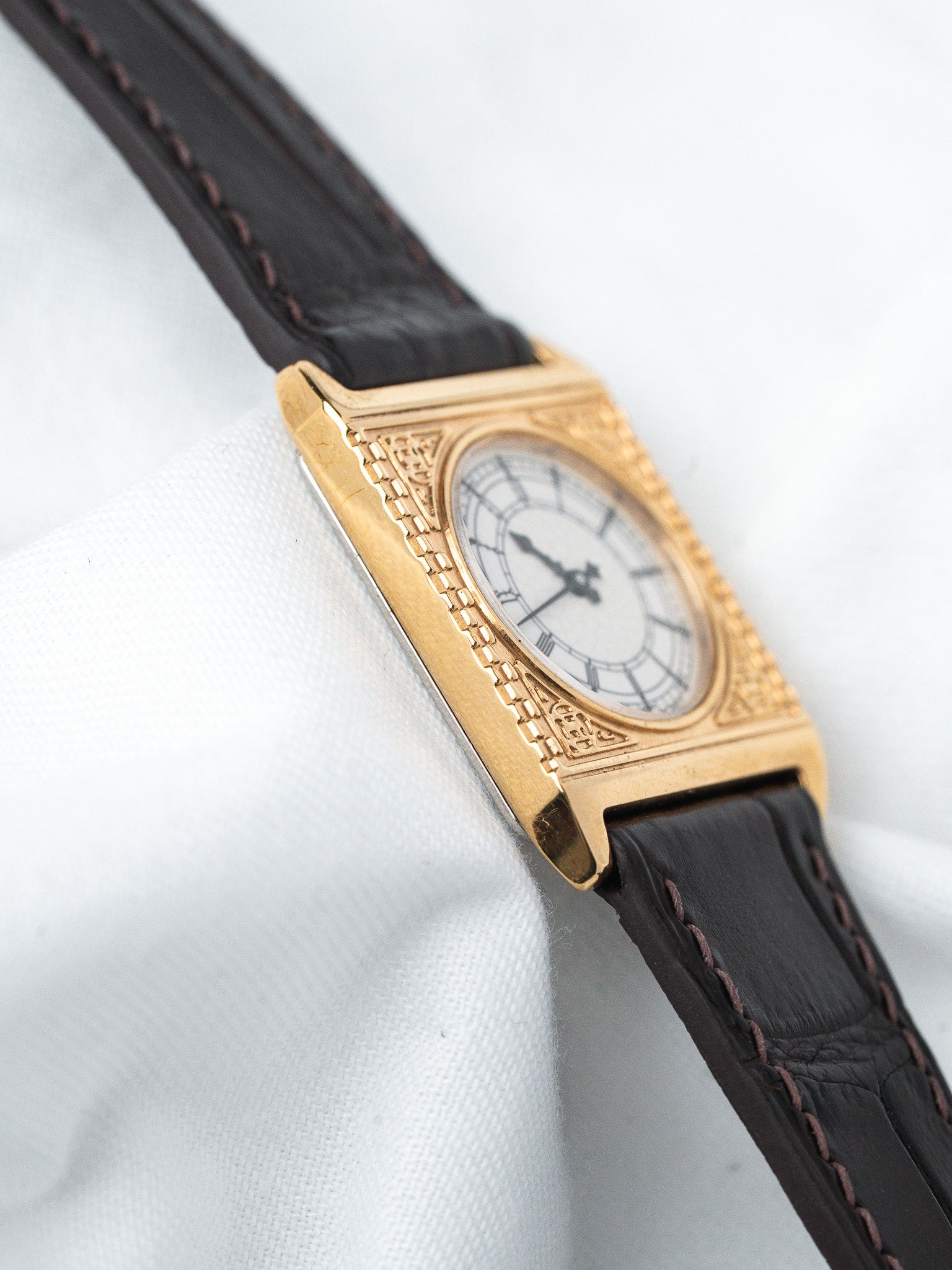 Vintage Cartier Tank watch with gold case, white dial, and black leather strap