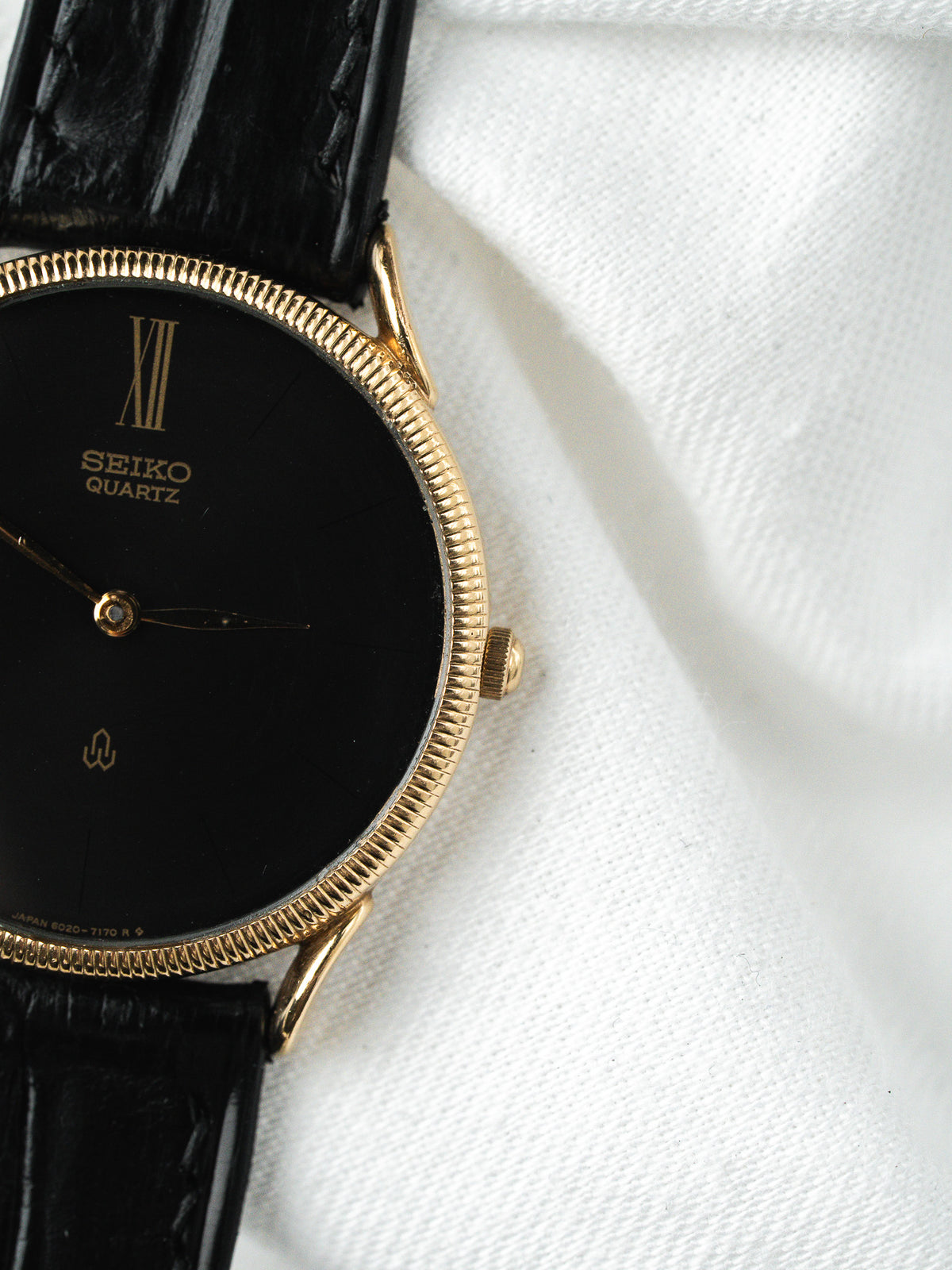 Montre Seiko vintage, boîtier doré, cadran noir et bracelet en cuir noir