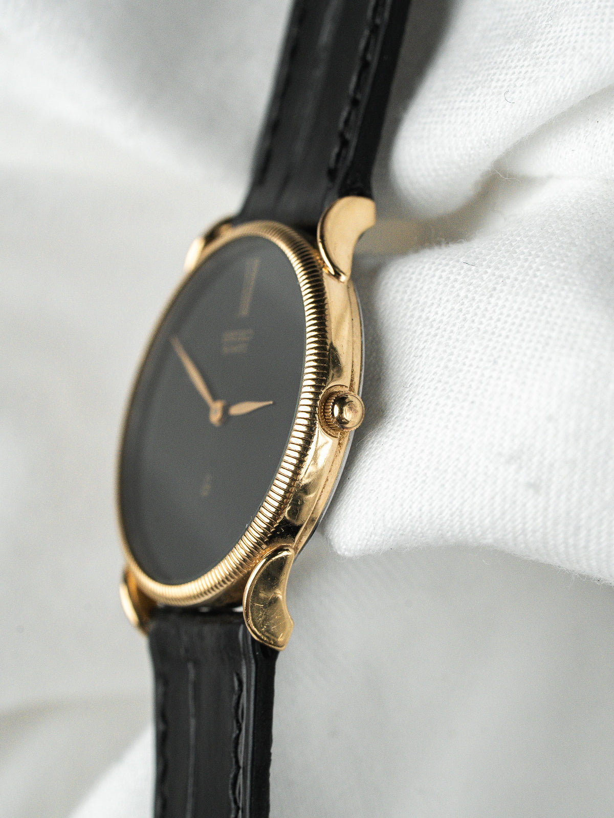 Montre vintage en or avec cadran noir et bracelet en cuir noir