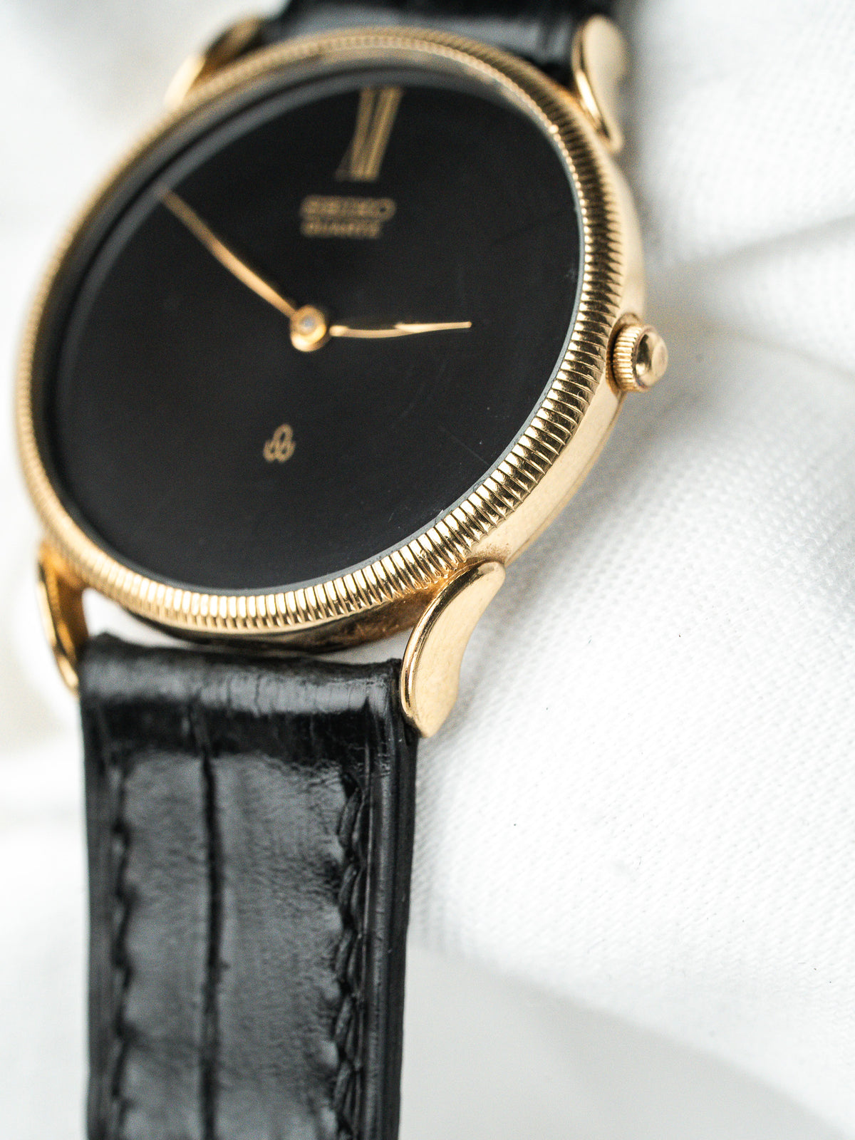 Montre Seiko vintage, boîtier plaqué or, cadran noir et bracelet en cuir noir