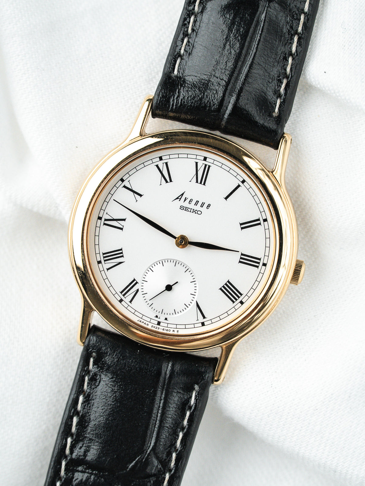Montre Seiko Avenue vintage, boîtier doré, cadran blanc et bracelet cuir noir