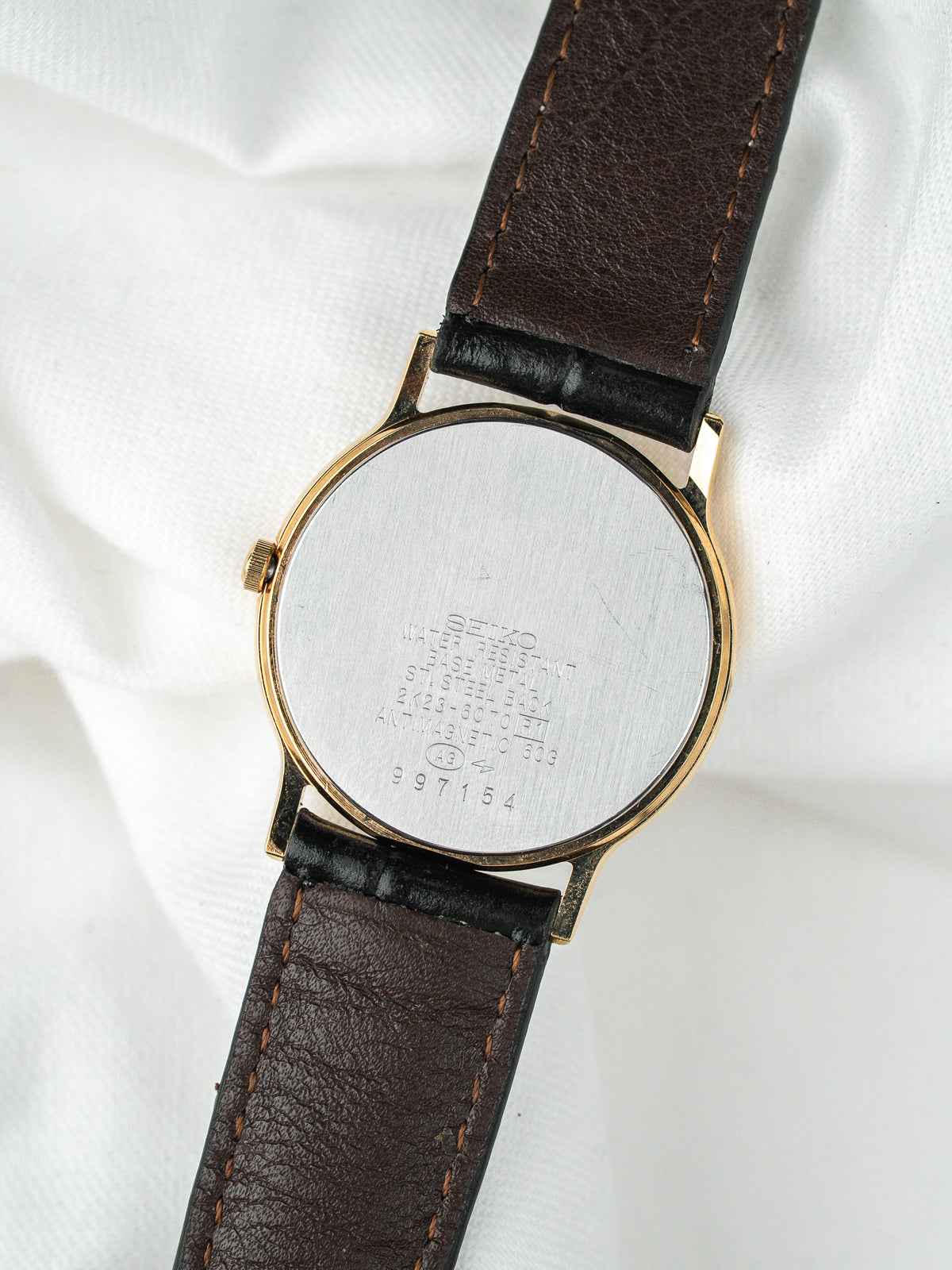 Dos d'une montre vintage avec boîtier doré et bracelet en cuir marron