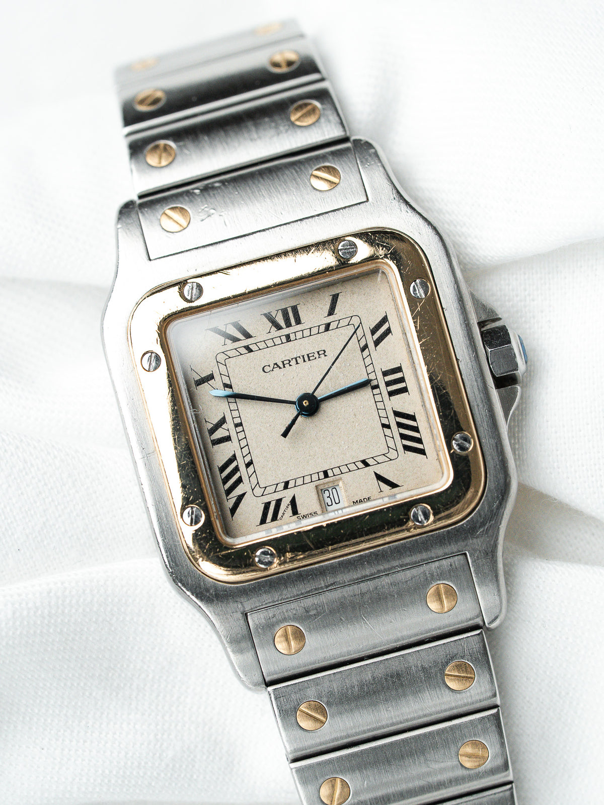 Montre Cartier vintage en acier, cadran blanc et boîtier rectangulaire sur fond blanc