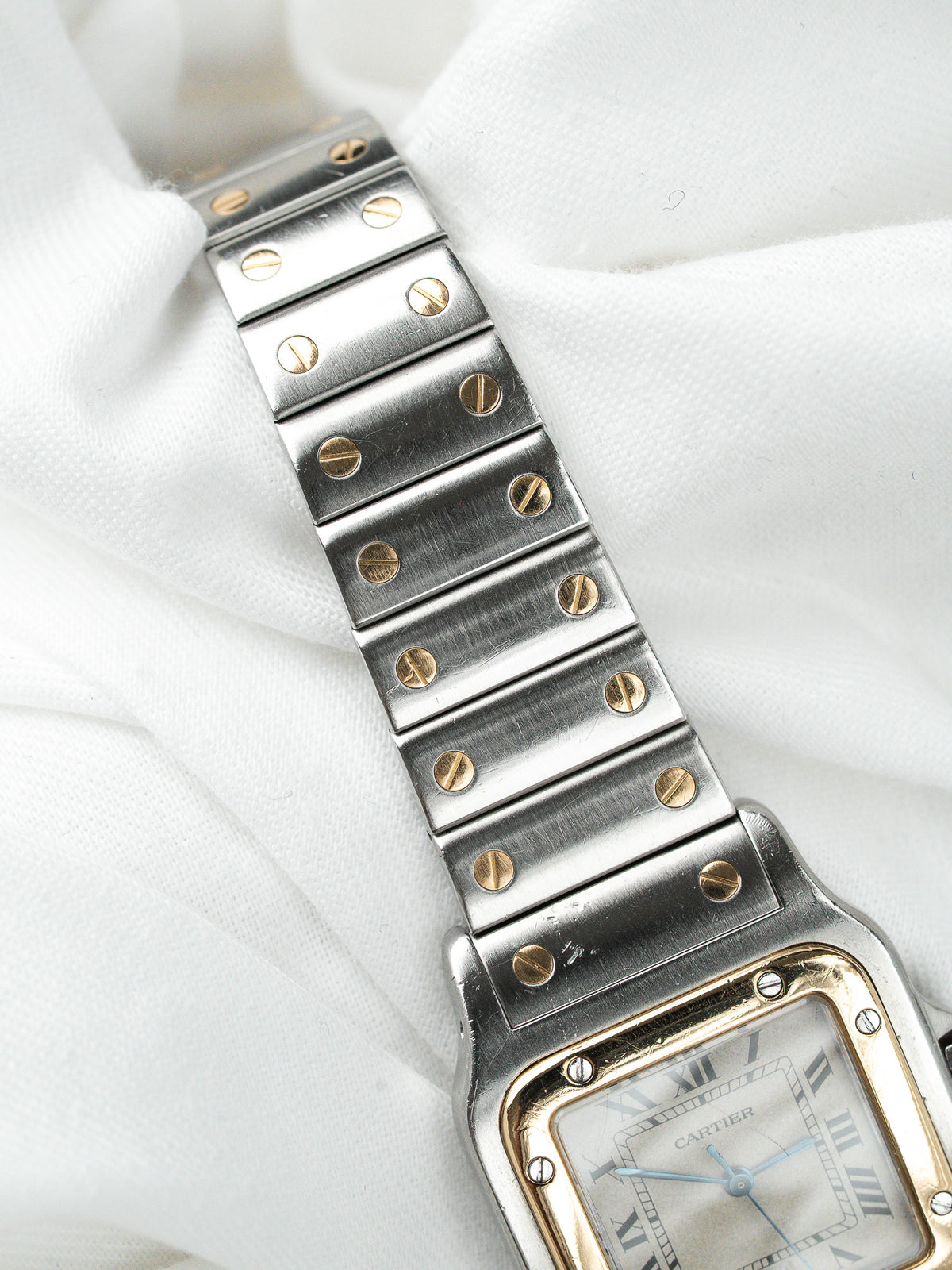 Montre Cartier vintage en acier avec bracelet à vis dorées sur fond blanc
