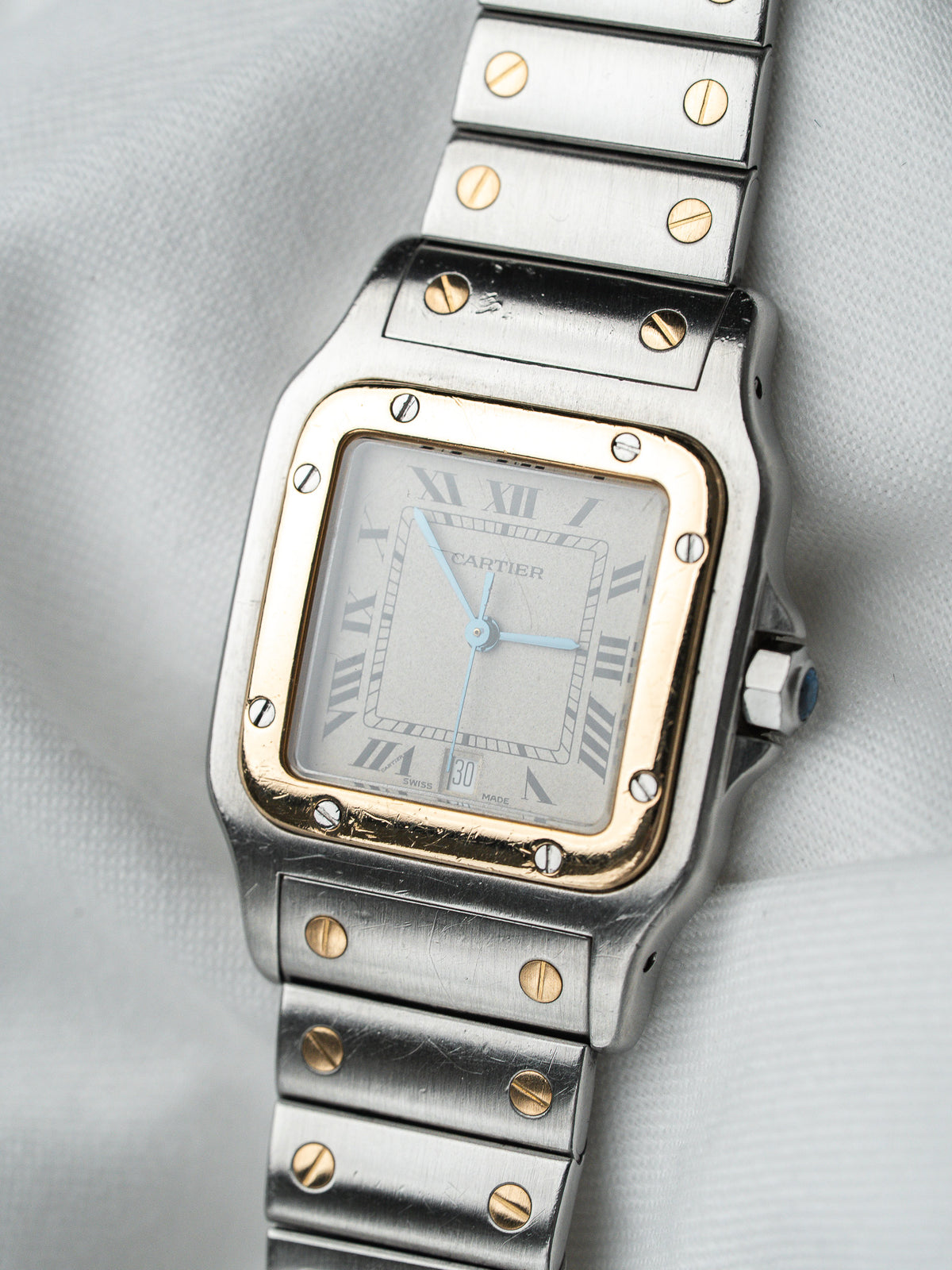 Montre Cartier vintage en acier et or, boîtier carré, cadran argenté sur fond blanc