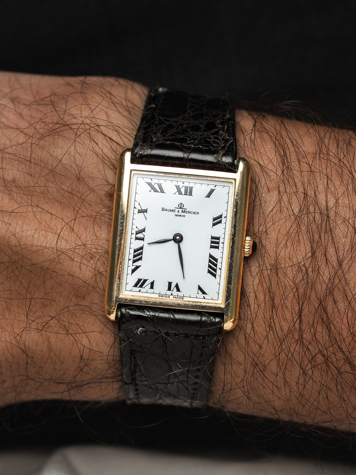 Montre Baume & Mercier vintage, boîtier rectangulaire doré, cadran blanc et bracelet cuir noir