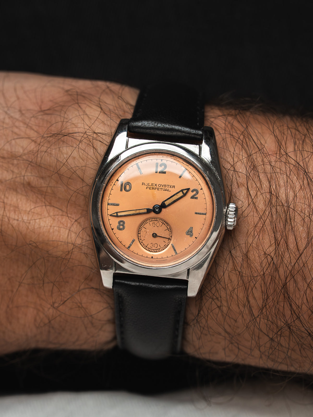 Montre Rolex Oyster Perpetual vintage, cadran saumon, bracelet cuir noir, portée au poignet