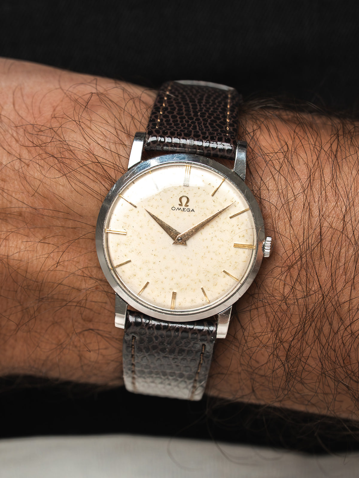Montre Omega vintage avec cadran crème et bracelet en cuir brun texturé.