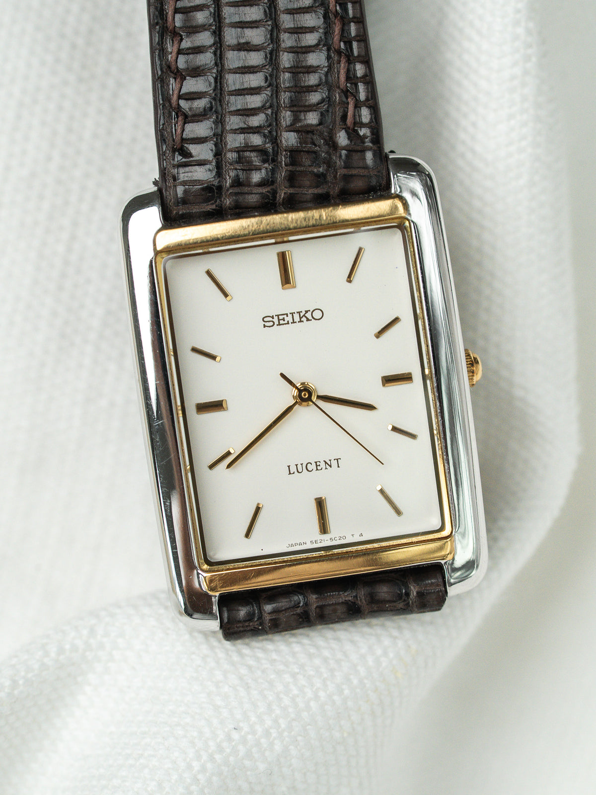 Montre Seiko Lucent vintage rectangulaire avec cadran blanc et bracelet en cuir brun.