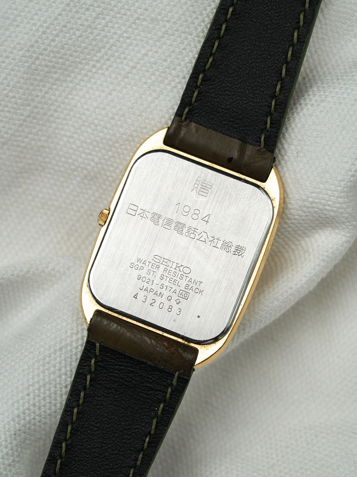 Dos d'une montre Seiko vintage en acier doré avec bracelet en cuir noir.