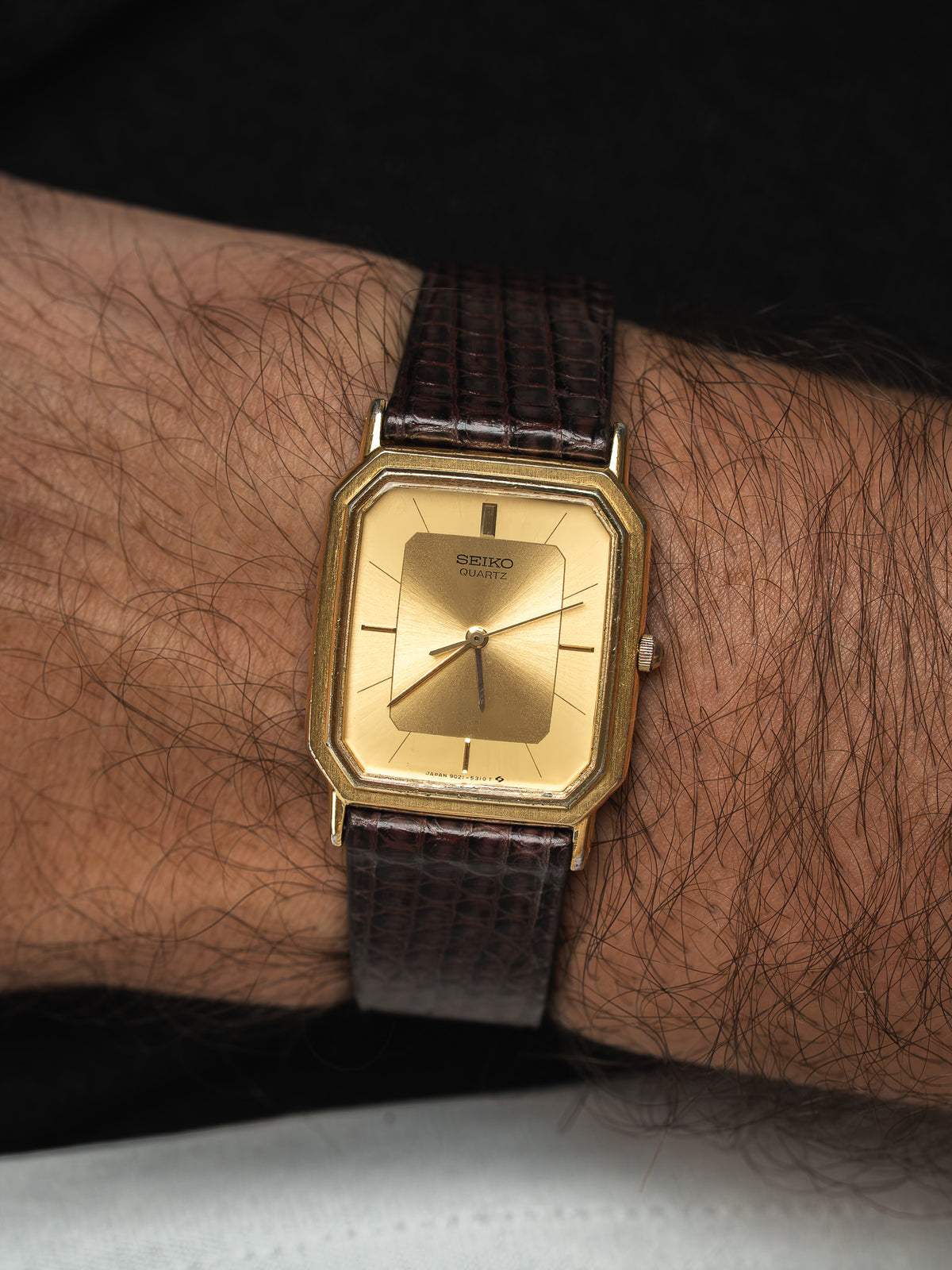 Montre Seiko Quartz vintage au boîtier doré et bracelet en cuir marron.