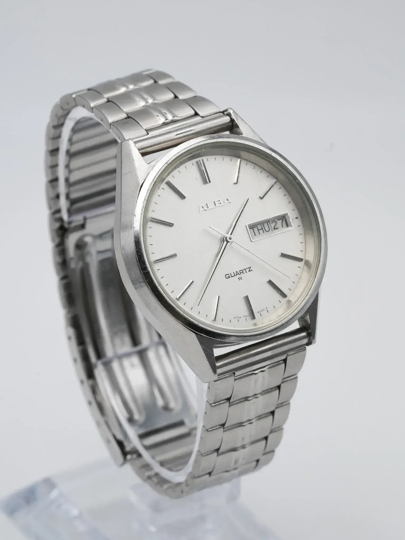 Alba vintage quartz watch with silver dial, day-date window, and steel bracelet on display stand