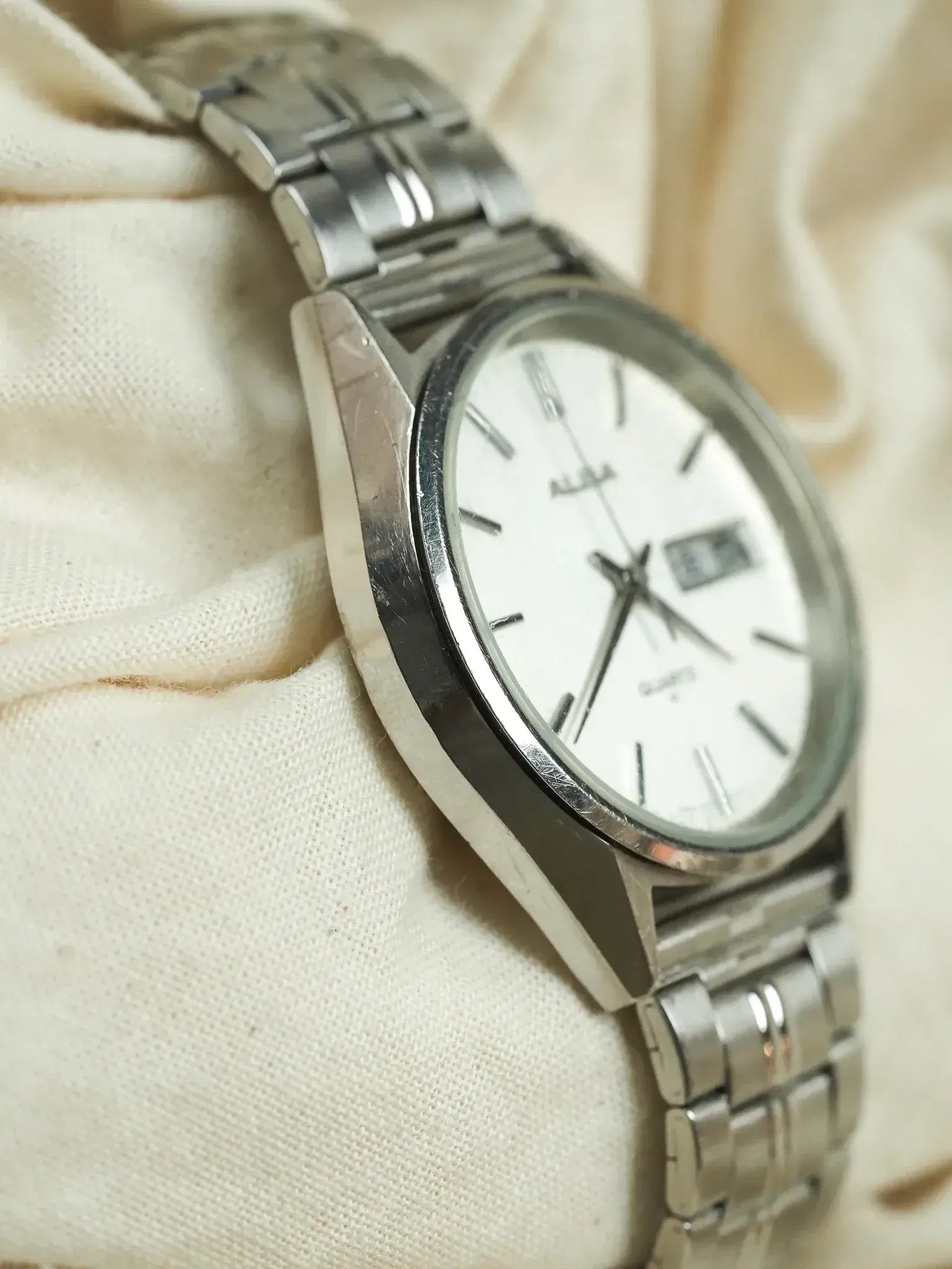 Alba vintage watch with white dial, steel bracelet, resting on cream fabric