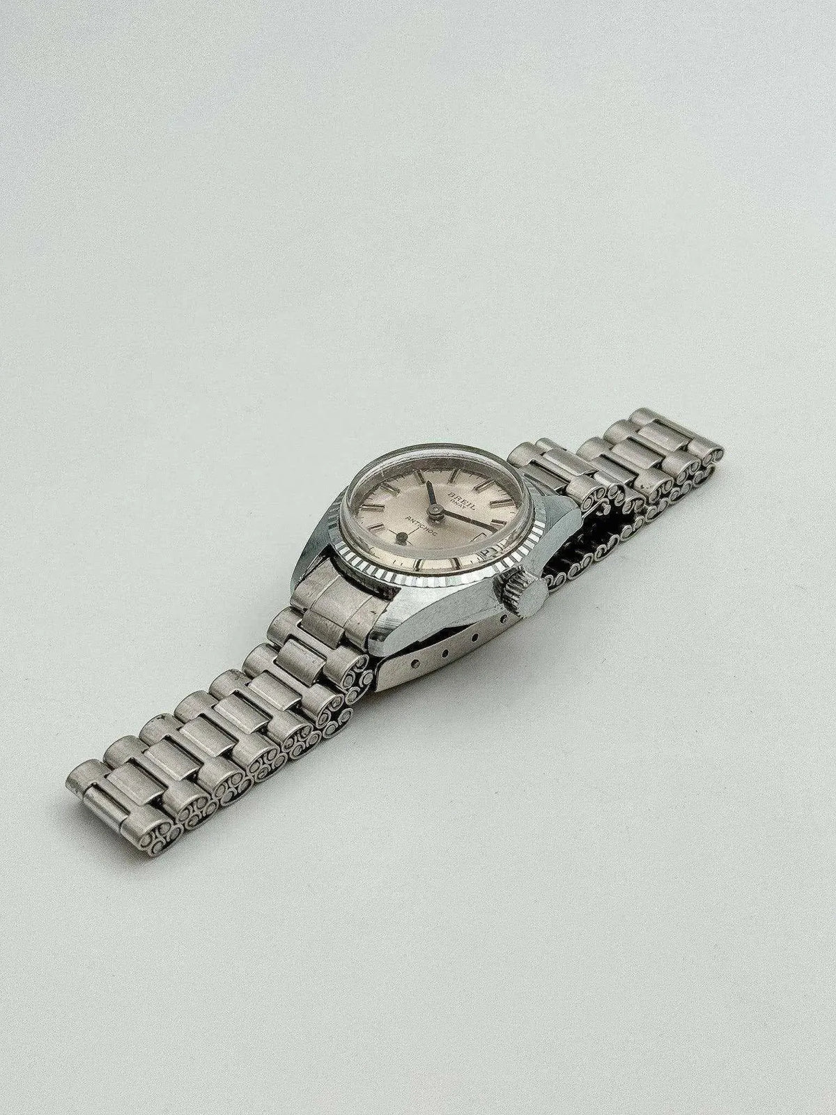 Brevet vintage watch with silver dial and steel bracelet on neutral background