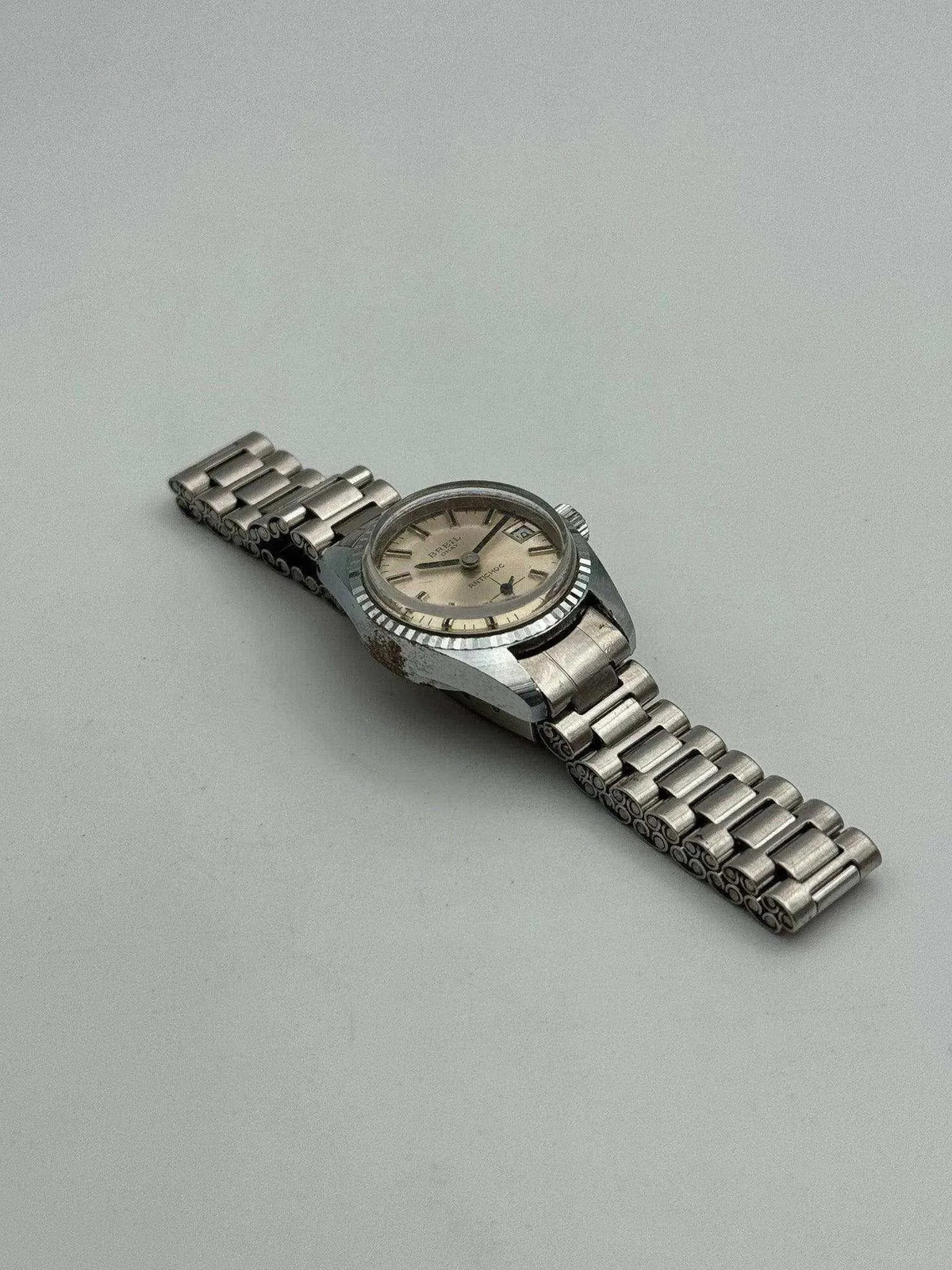 Vintage Doxa Sub 300T watch with steel bracelet, cream dial, and textured bezel on neutral background