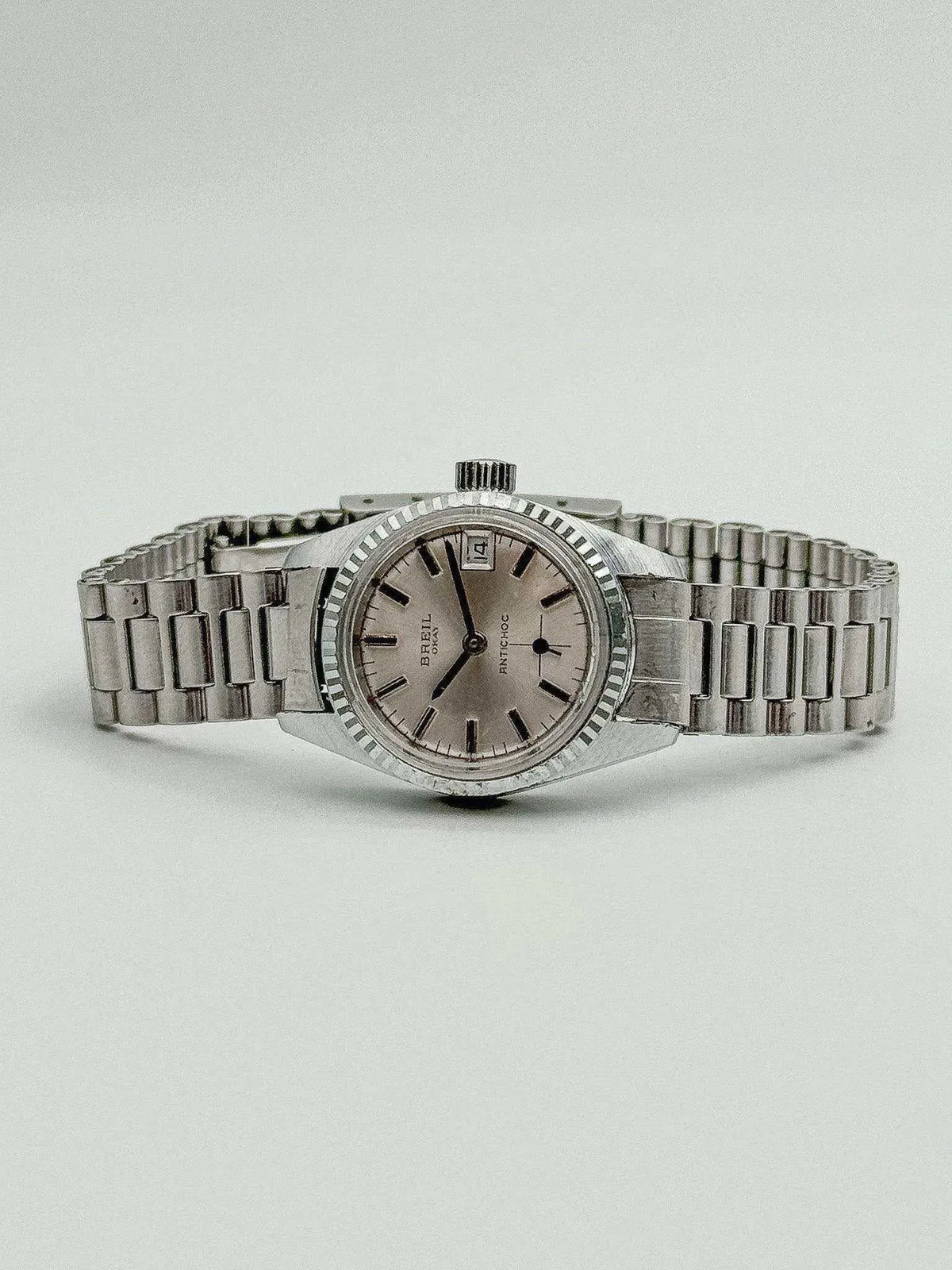 Vintage Breil Antichoc watch with silver dial, steel bracelet, and fluted bezel on neutral background