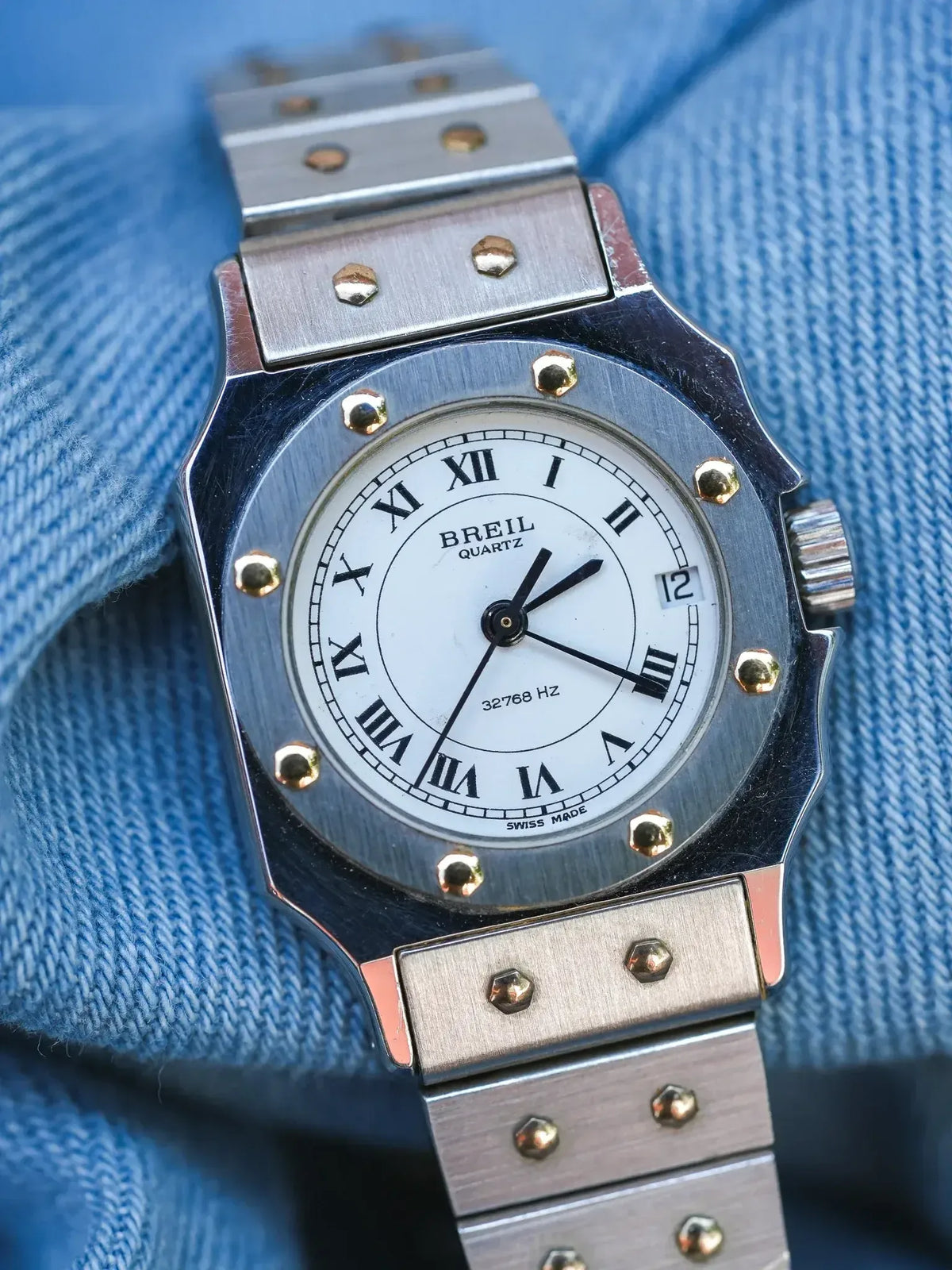 Breil quartz watch with white dial, Roman numerals, and brushed steel bracelet on denim
