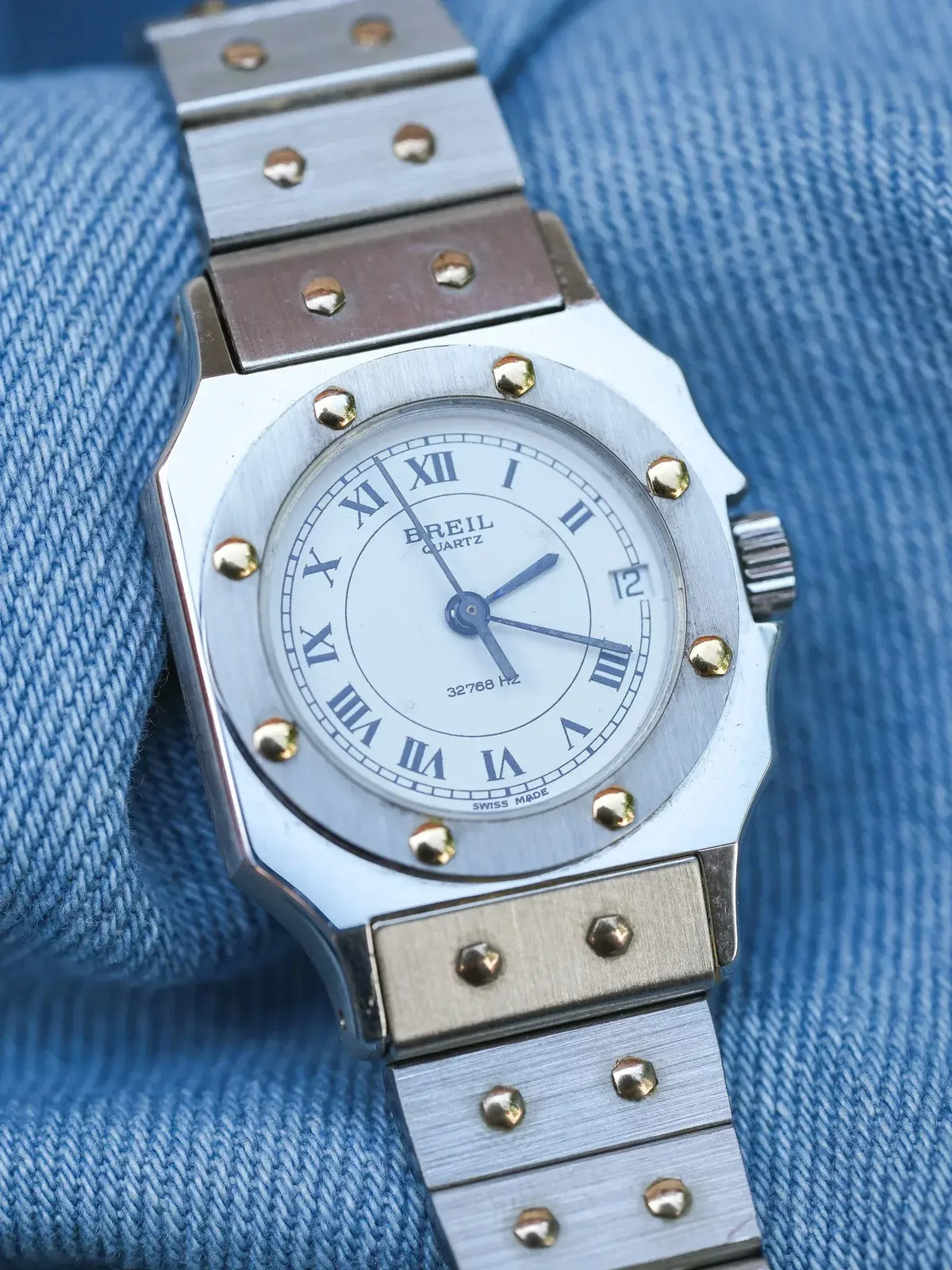 Breil quartz watch with white dial, Roman numerals, and gold-tone accents on denim