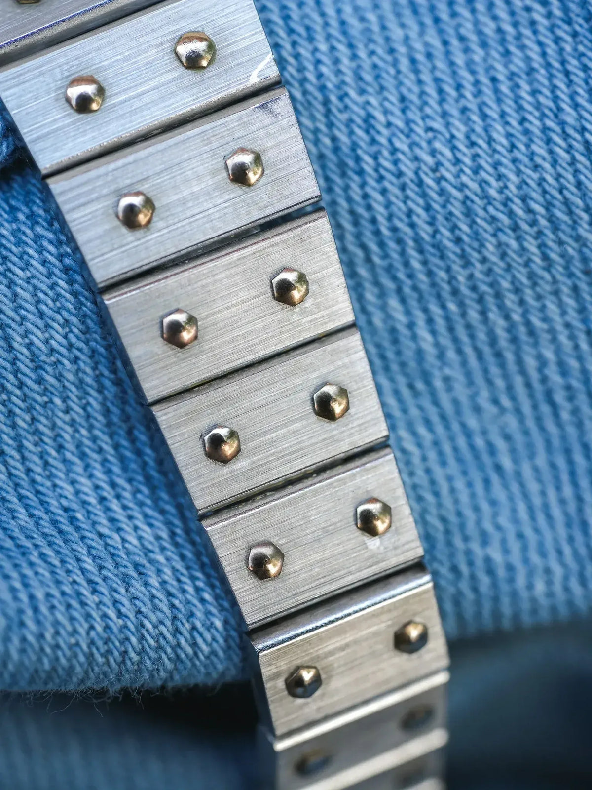 Vintage Rolex Oyster bracelet with brushed steel links and gold screws on denim