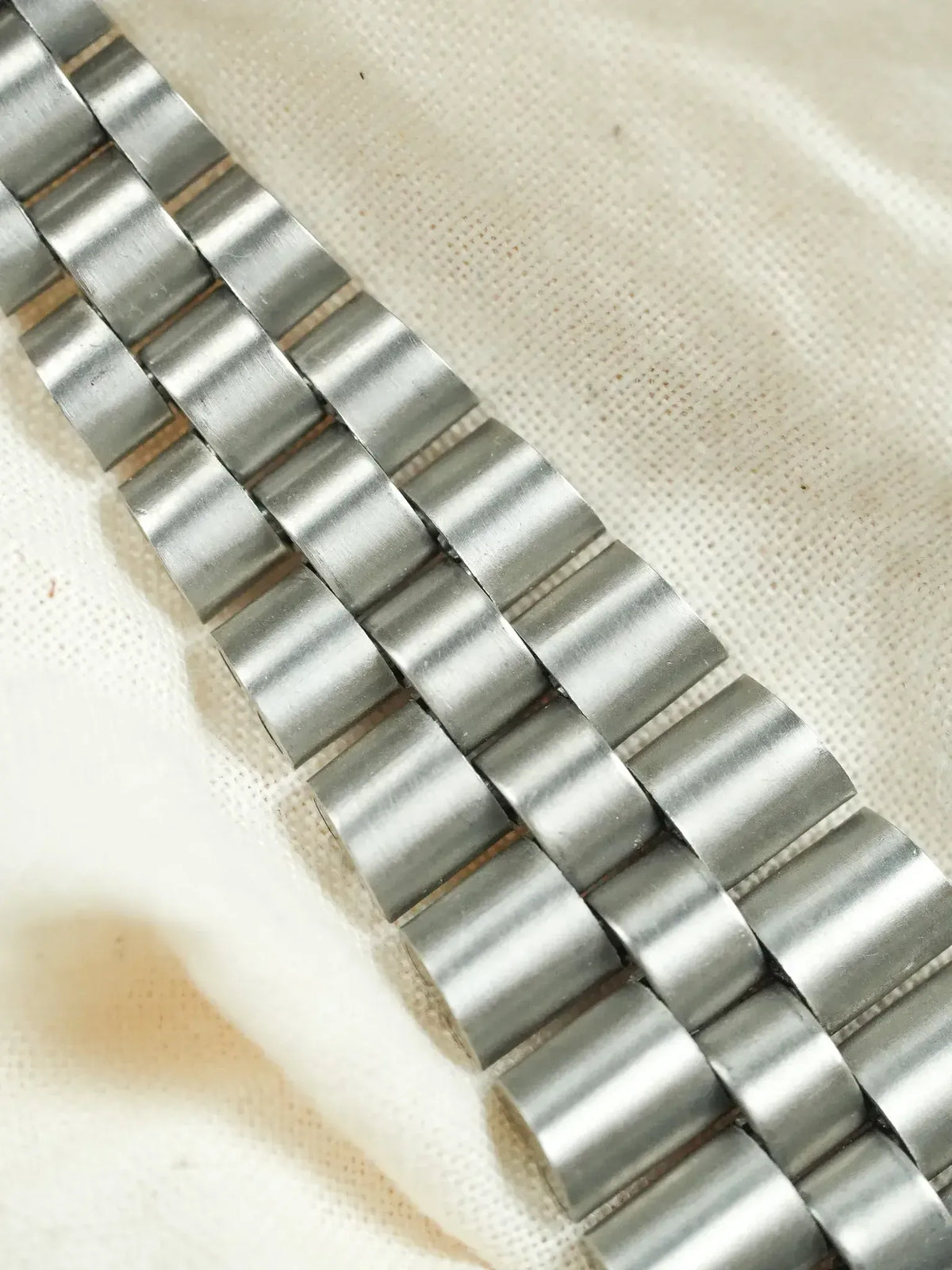 Vintage Rolex Oyster bracelet in brushed stainless steel on fabric background