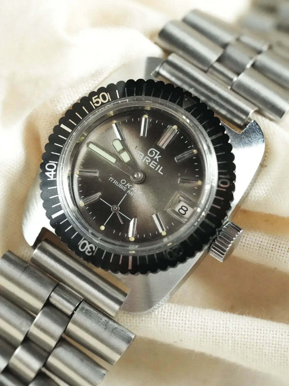 Vintage GK Breil Okar watch with black dial, steel bracelet, and rotating bezel