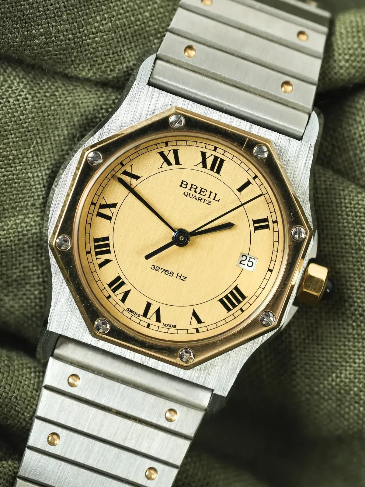 Breil quartz vintage watch with gold dial, Roman numerals, steel bracelet on olive fabric