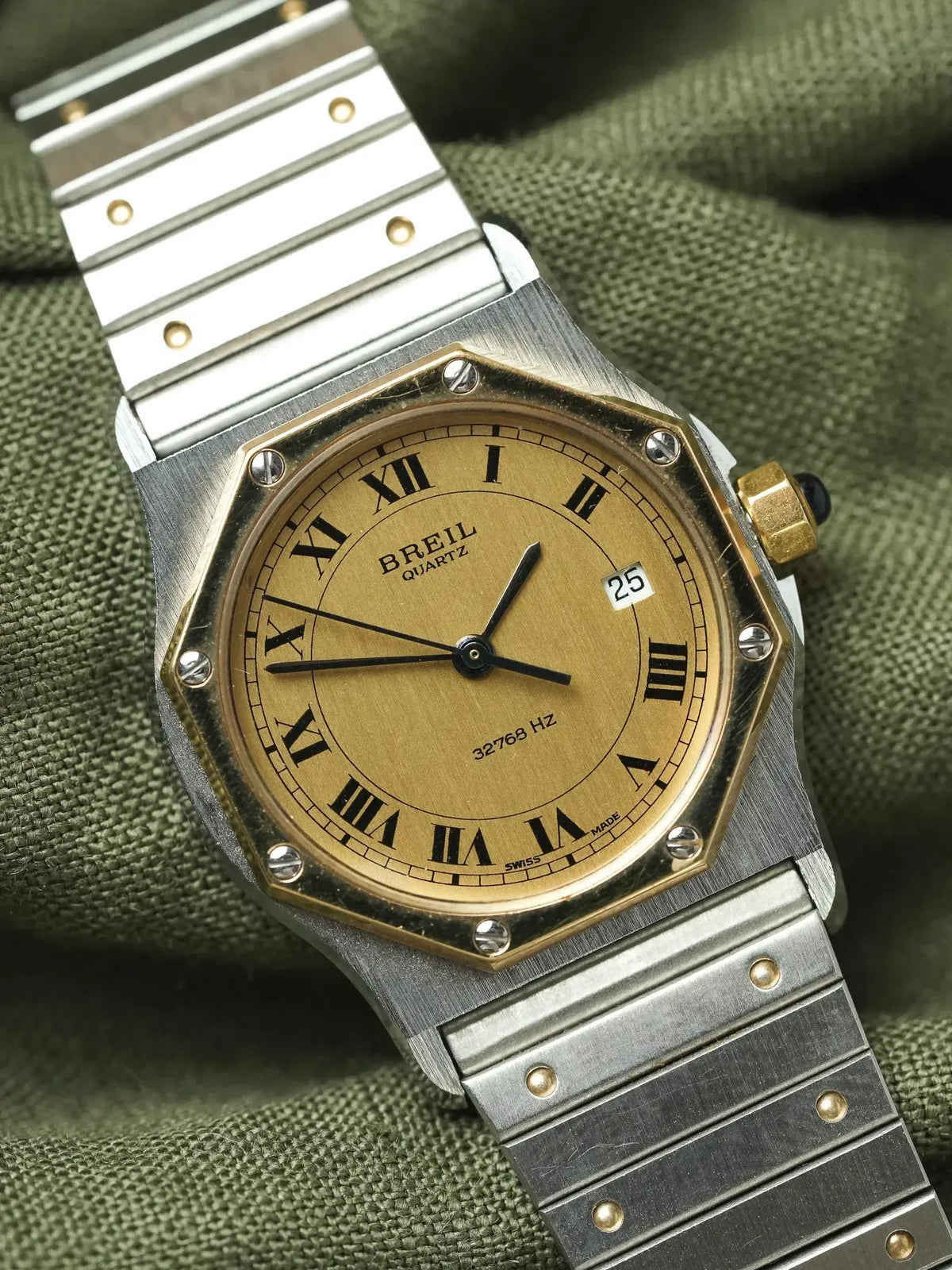 Breil quartz watch with gold dial, Roman numerals, steel bracelet on green fabric
