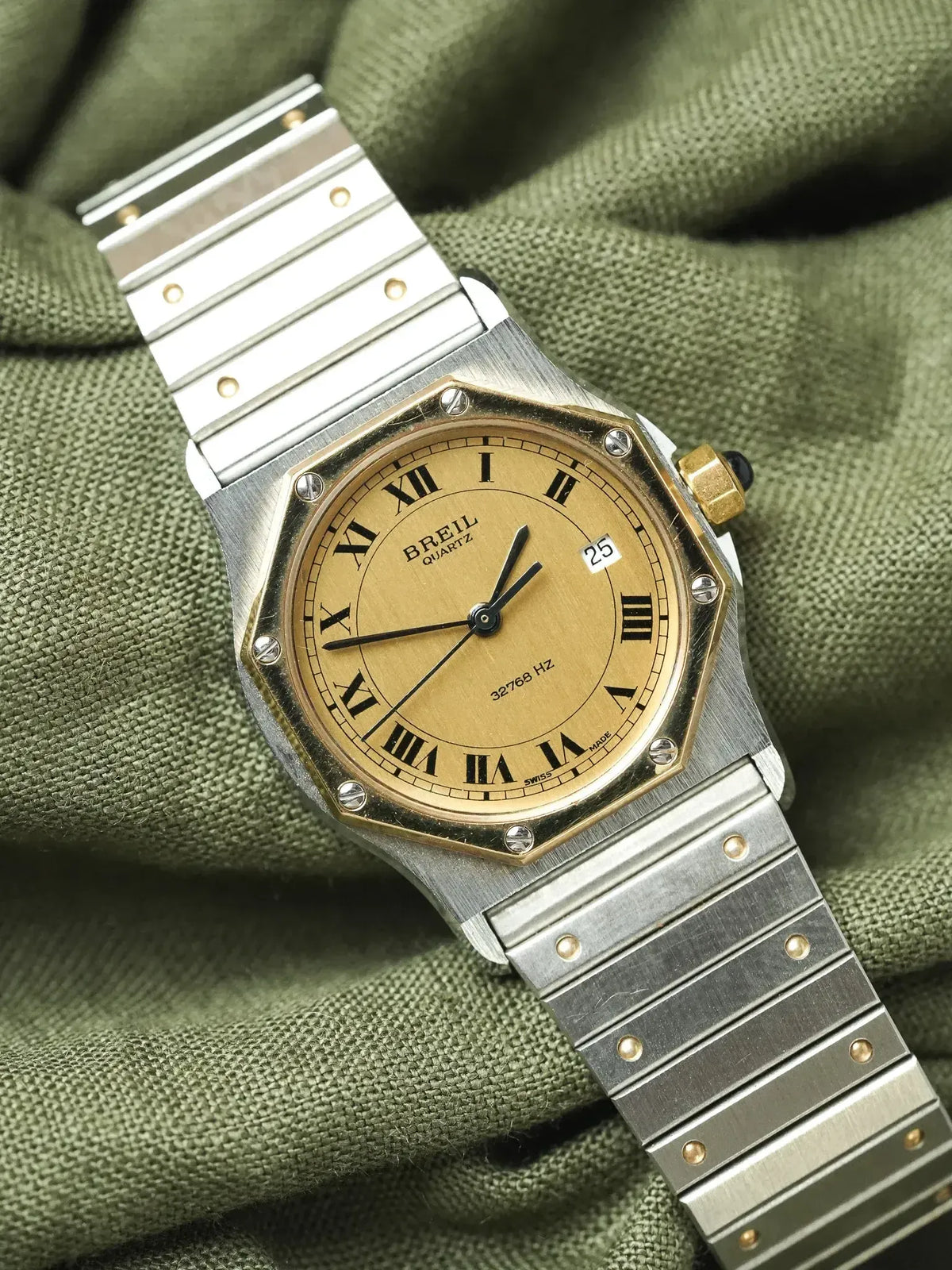 Breil quartz watch with gold dial, Roman numerals, steel bracelet on green fabric