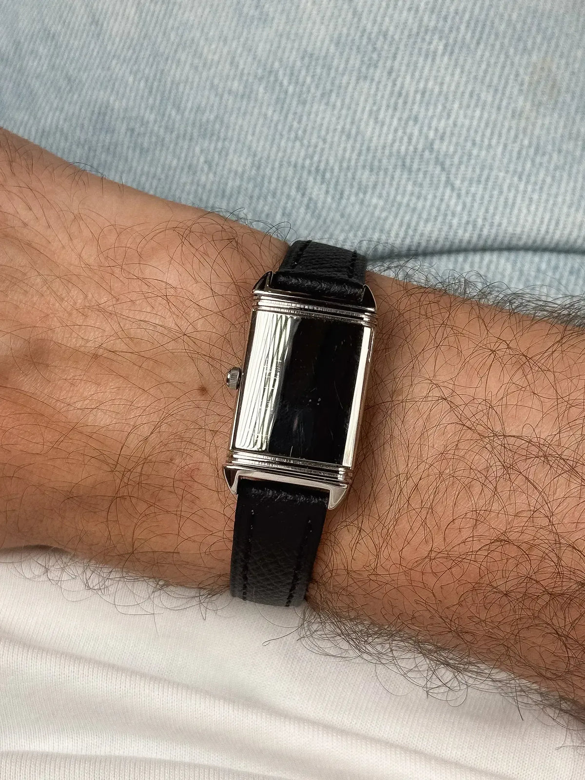 Vintage Cartier Tank watch with black dial, silver case, black leather strap on wrist