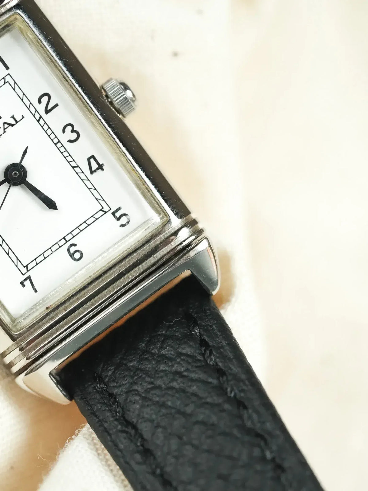 Universal Genève vintage watch with white dial, black numerals, and black leather strap